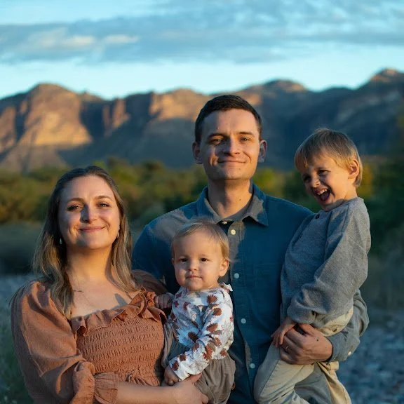 A family of four outdoor at sunset with mountains in the background, smiling for the camera.