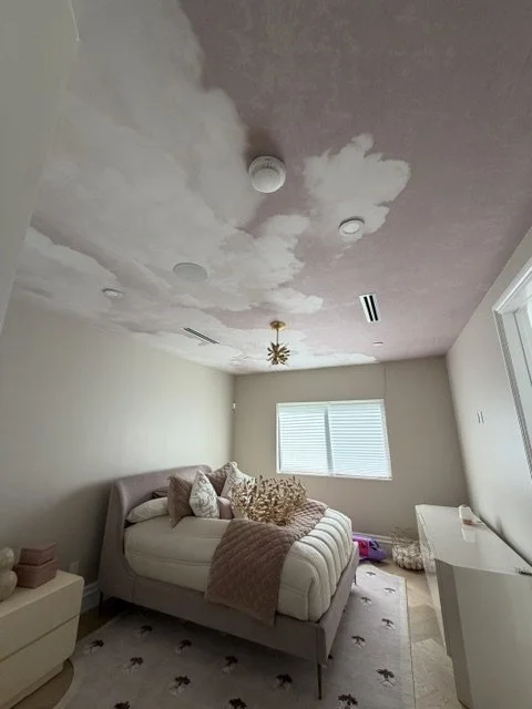 Cloud mural wallpaper installed across a bedroom ceiling