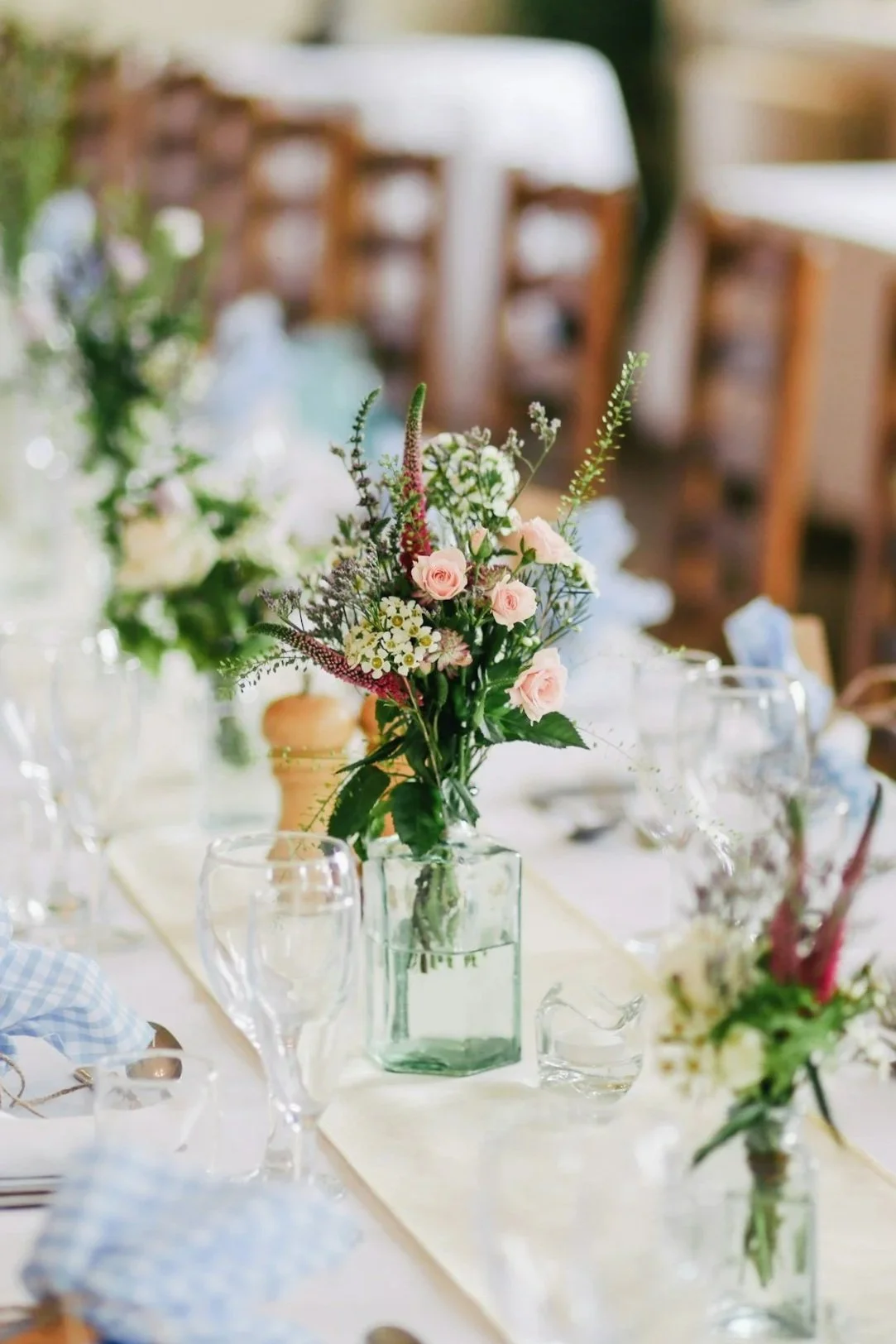 Table centerpieces with fresh flowers in glass vases at a formal event.