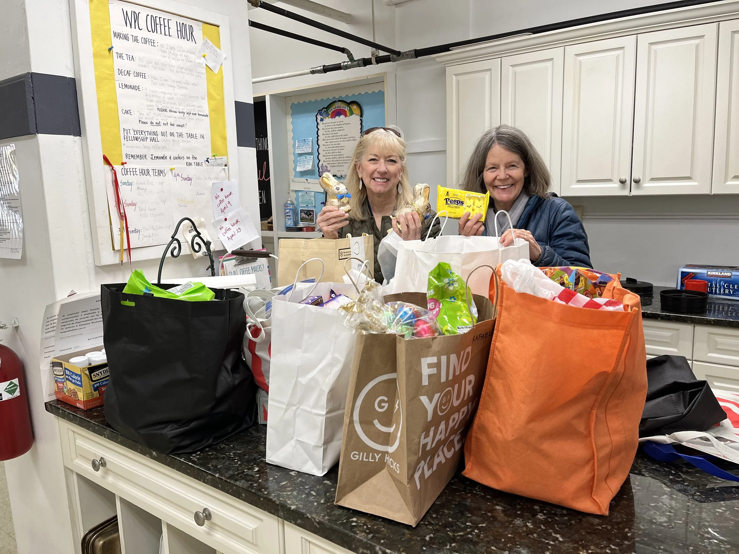 Two women smiling in front of the bags of groceries to give to Family Promise families