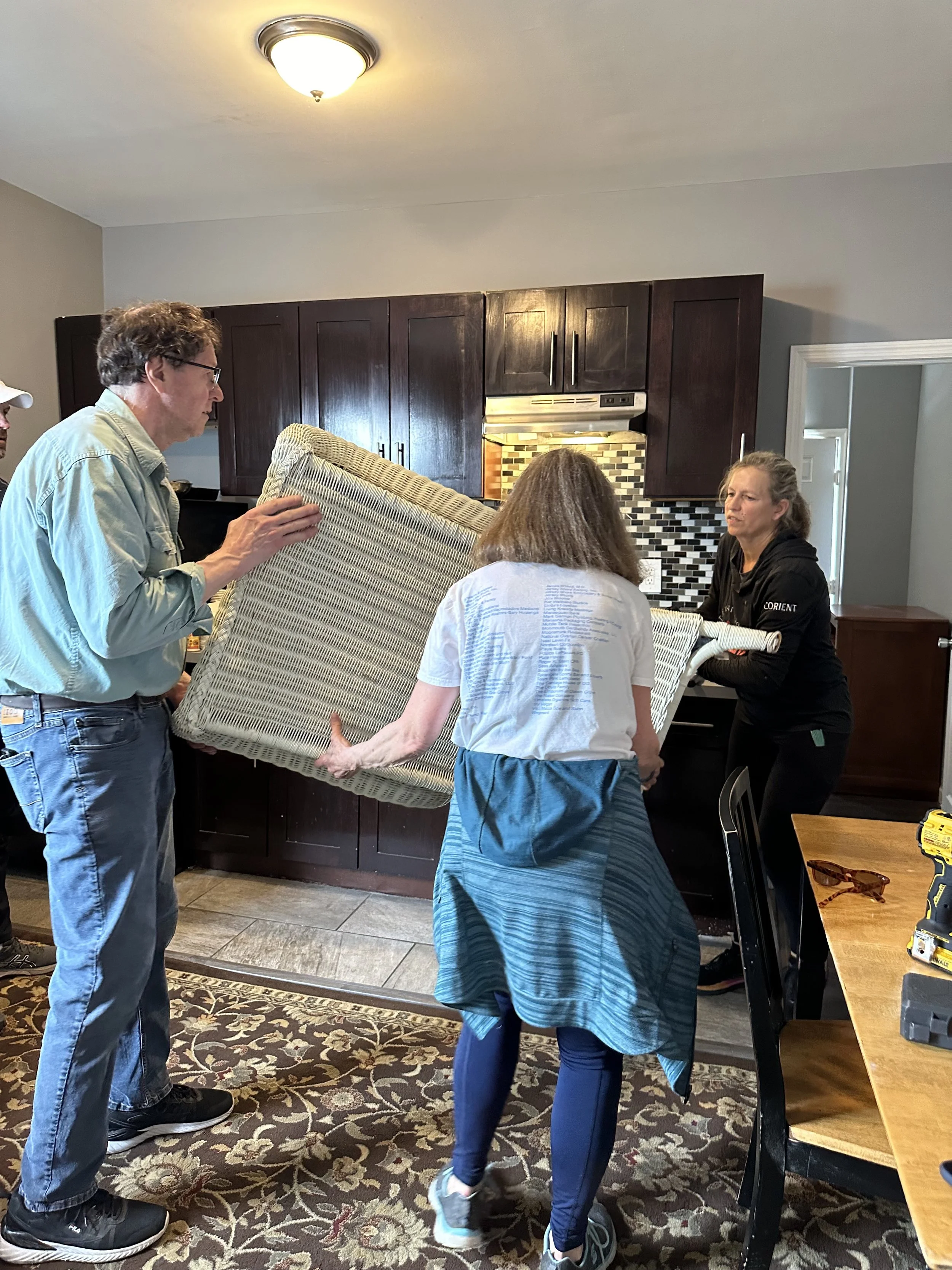 Four people helping move furniture into a new apartment for a formerly homeless family with The Warehouse NJ