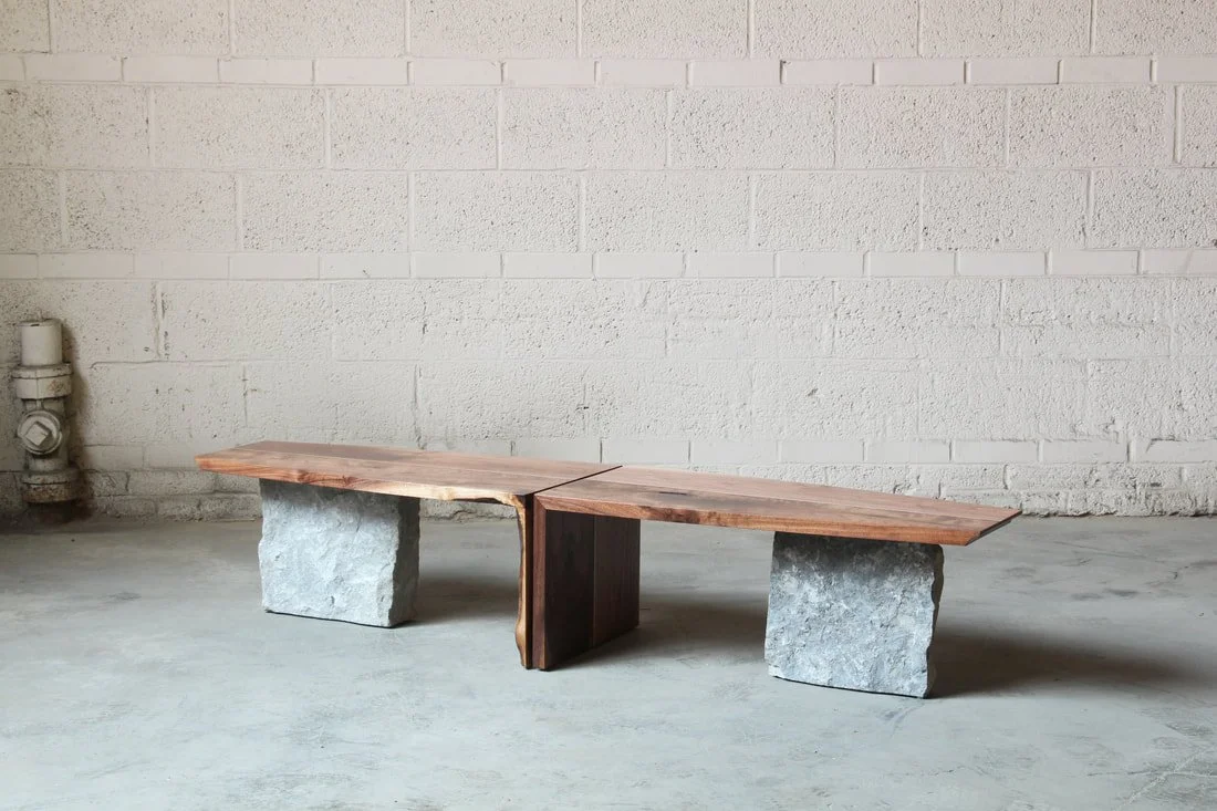 Modern bench with a wooden top and stone supports in an industrial space.