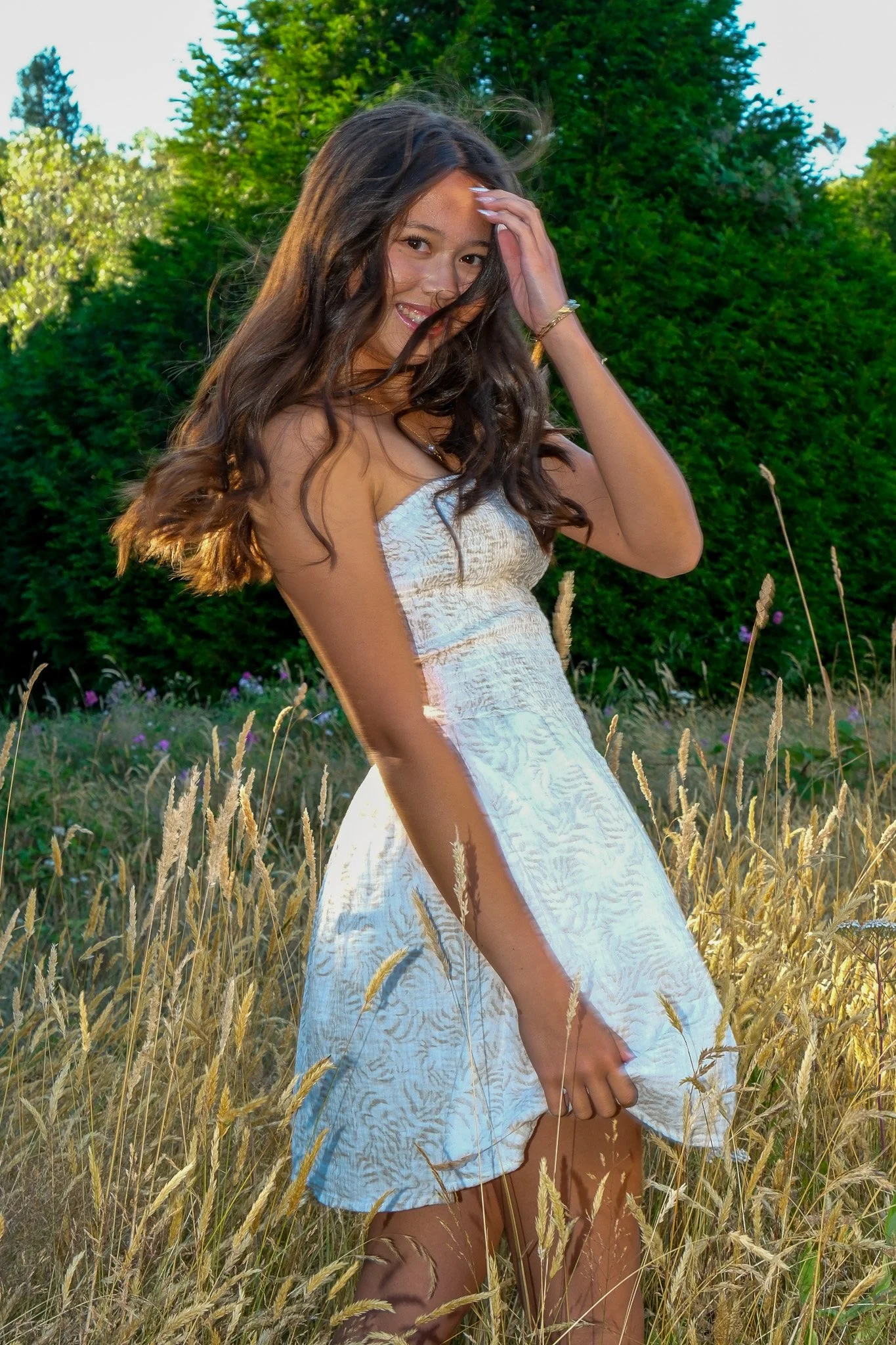 Senior Portrait of a girl in white dress in a field at golden hour in Discovery Park Seattle