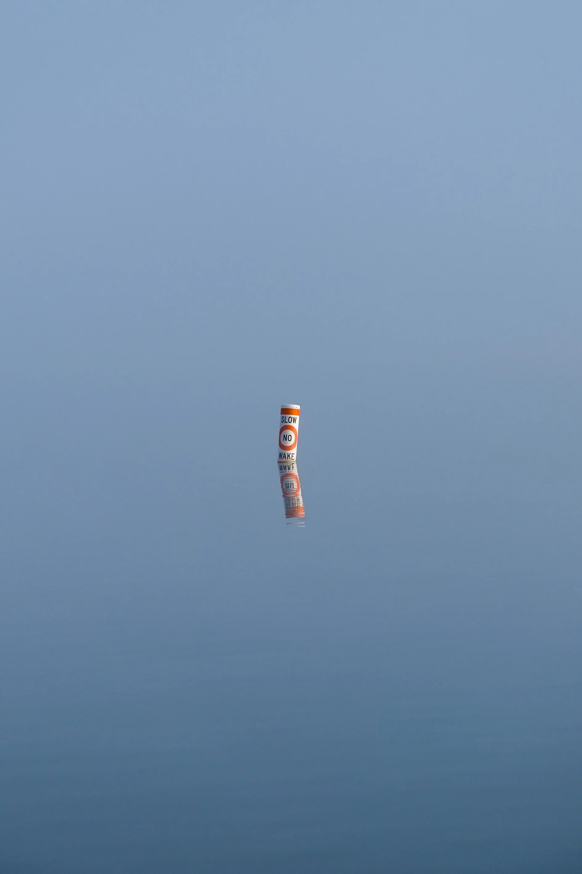 A buoy floating on a calm body of water with a clear sky in the background.