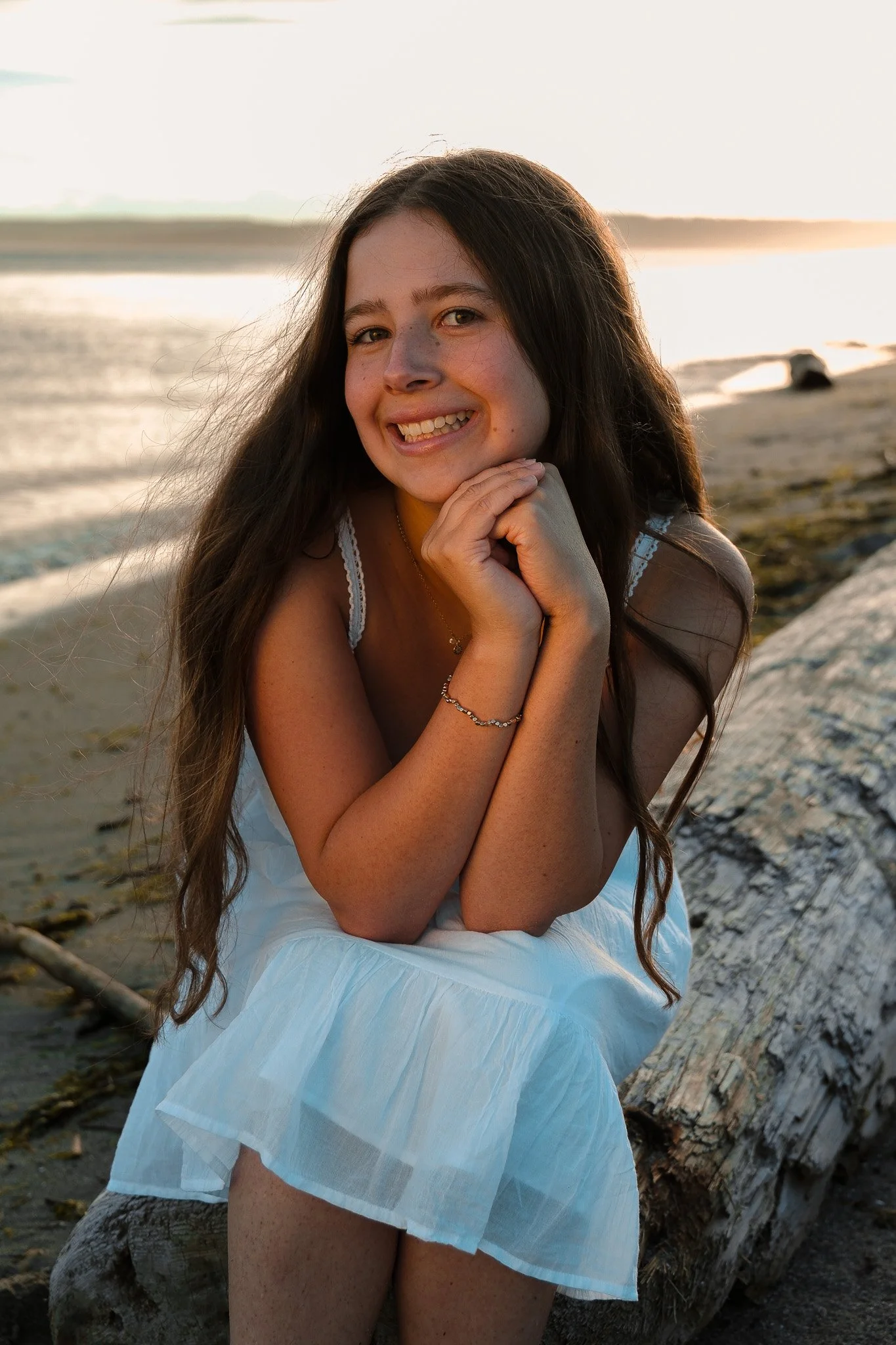 Girl sitting on the beach on a log Senior Portrait, West Point Beach