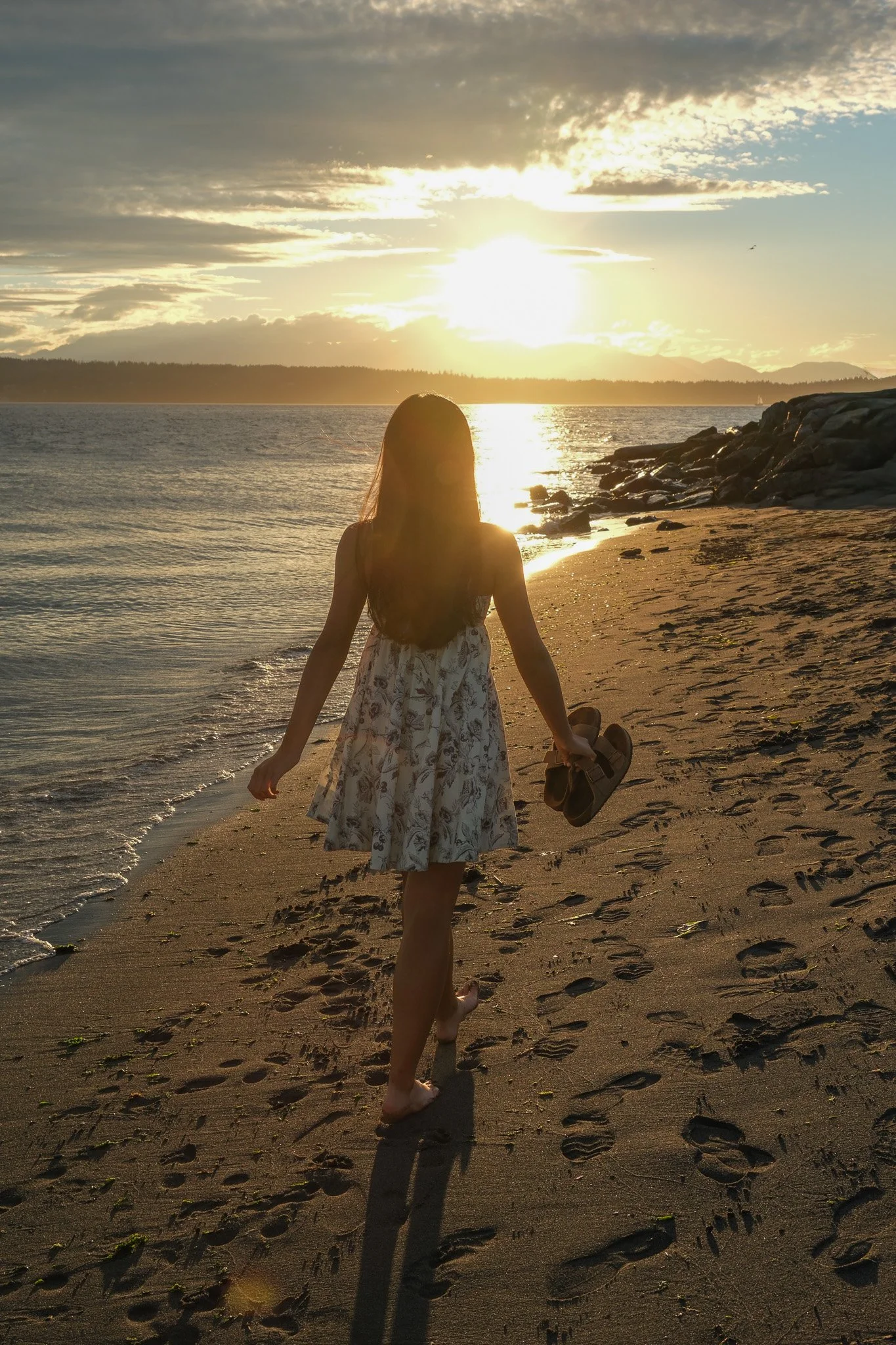 Senior Portrait of a girl walking along the beach holding her shoes in Discovery Park Seattle Washington 