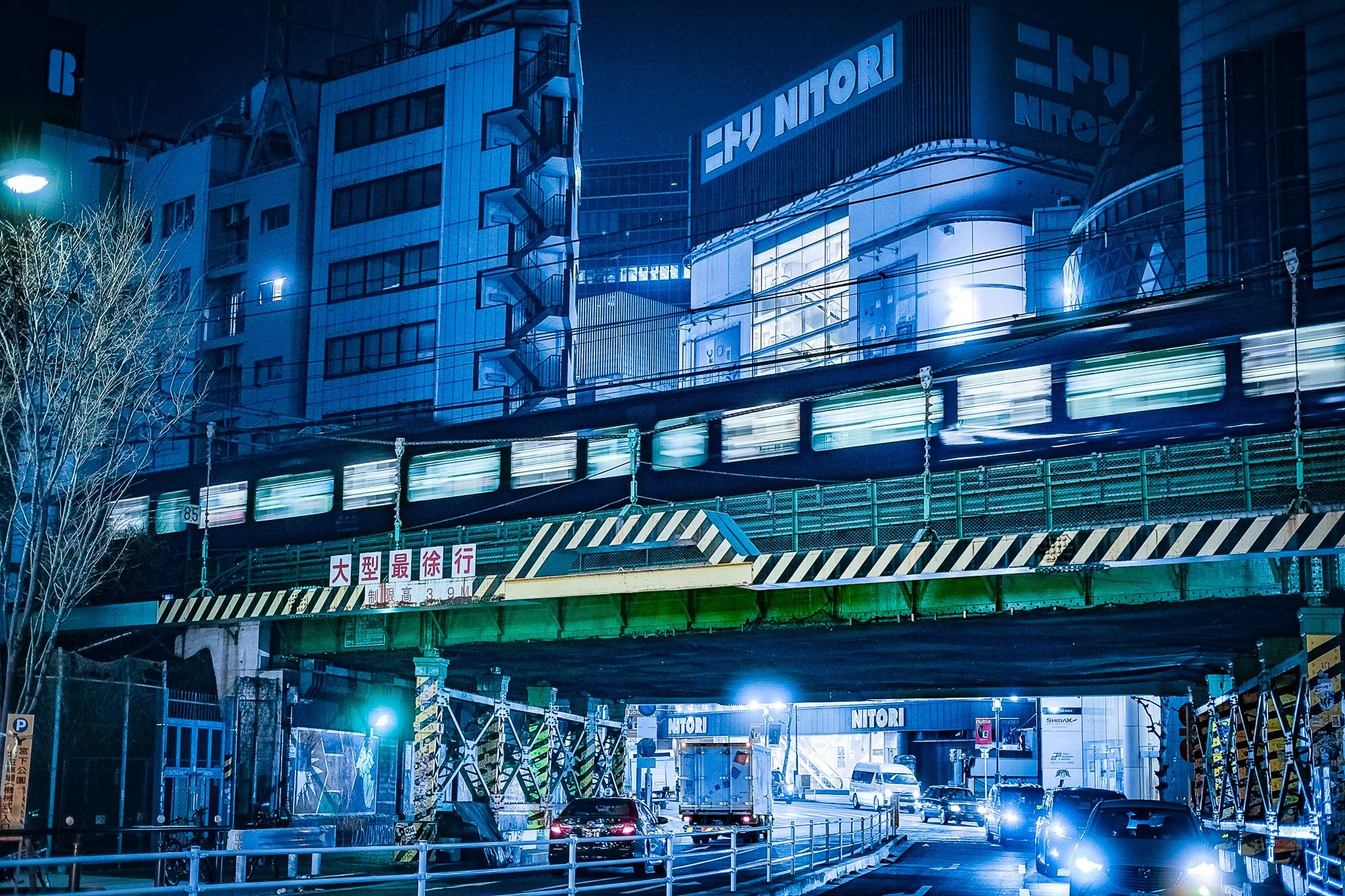 Long exposure night photography of a JR Yamamote line train passing through the neon-lit streets of Shibuya Tokyo.