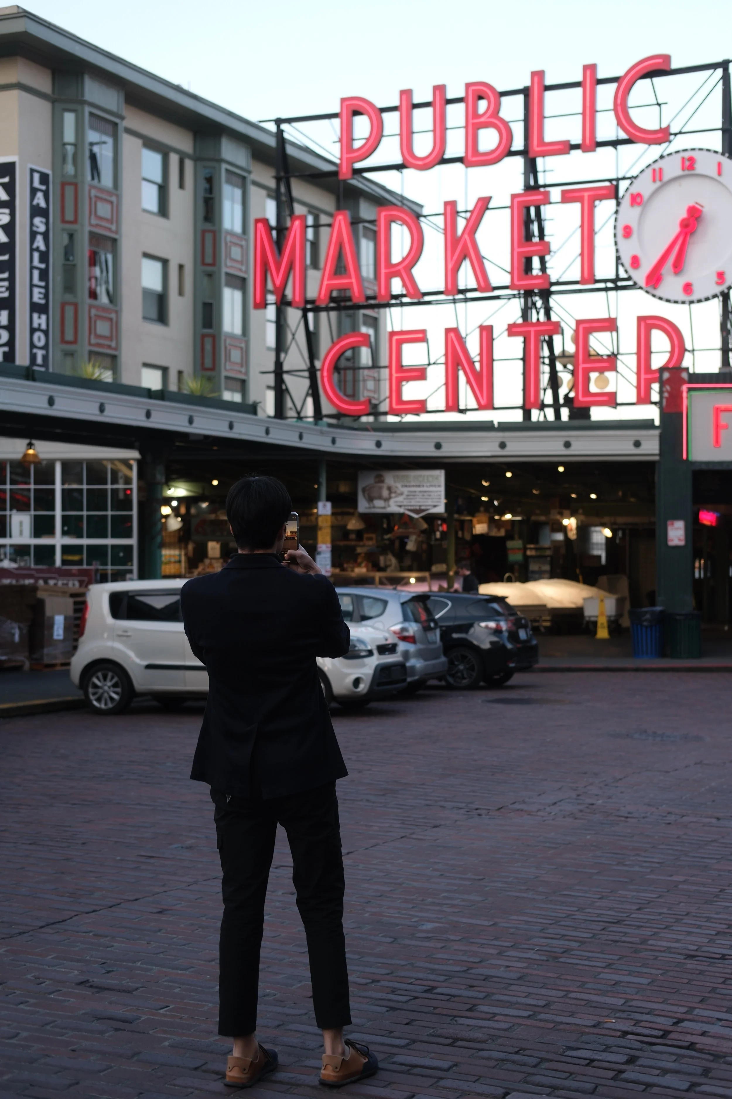 Photo of a man taking a photo of the Pike Place Market sign in Seattle Washington 