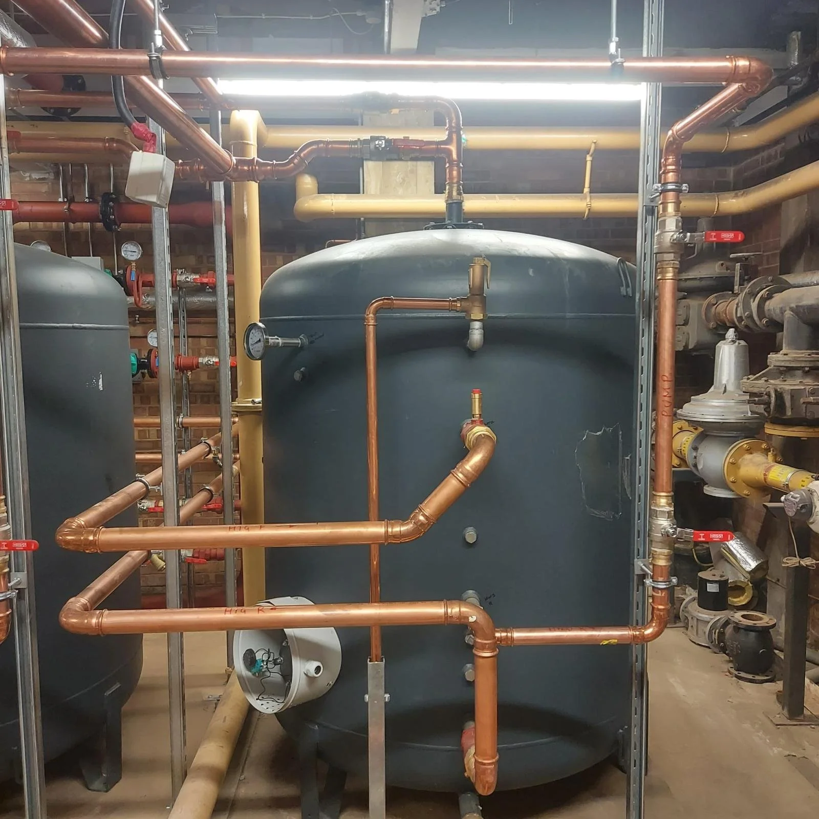 A large industrial boiler system with copper pipes, gauges, and valves installed in a mechanical room.
