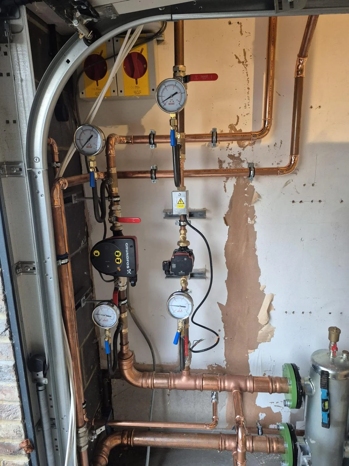 Plumbing system with copper pipes, pressure gauges, valves, and a Grundfos pump.