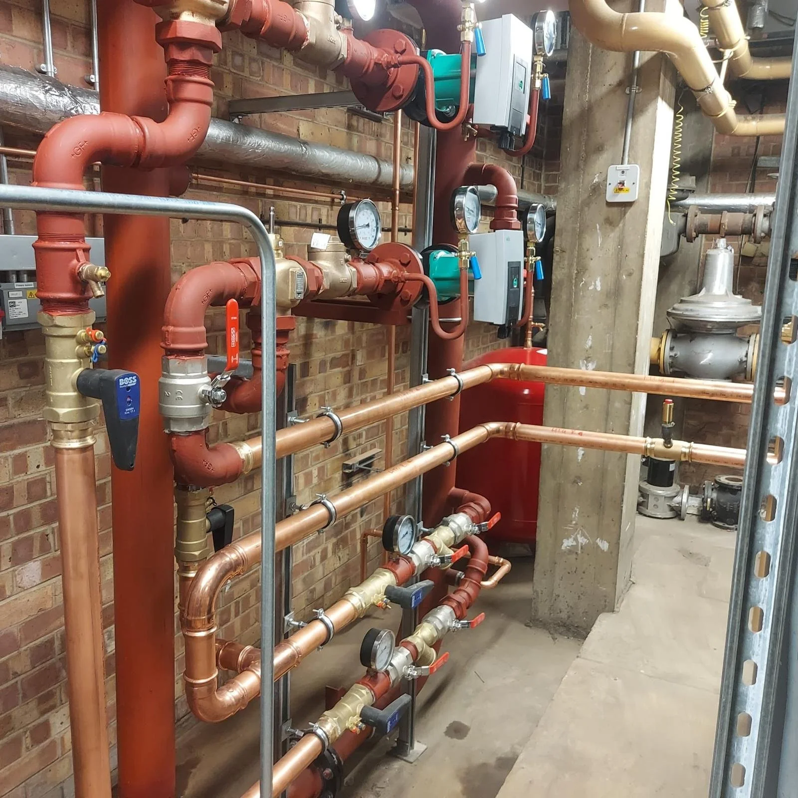 A utility room with an extensive network of pipes, gauges, and control valves, presumably part of a building's heating, cooling, or plumbing system.