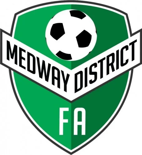 Logo of Medway District FA featuring a shield with a soccer ball at the top and the text 'Medway District FA' across the center in black letters on a white banner, with a green background.