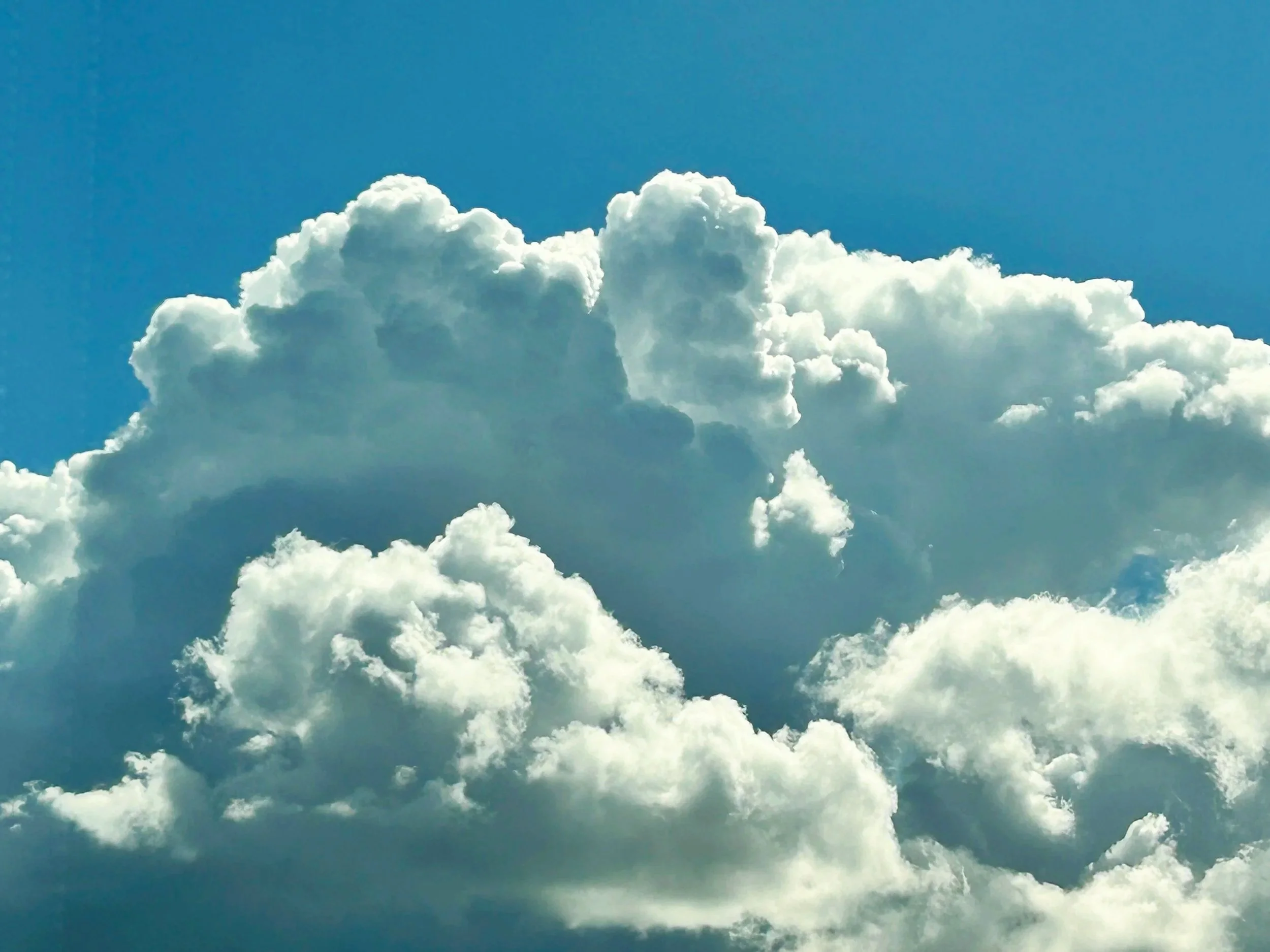 A bright blue sky with large, fluffy white clouds.