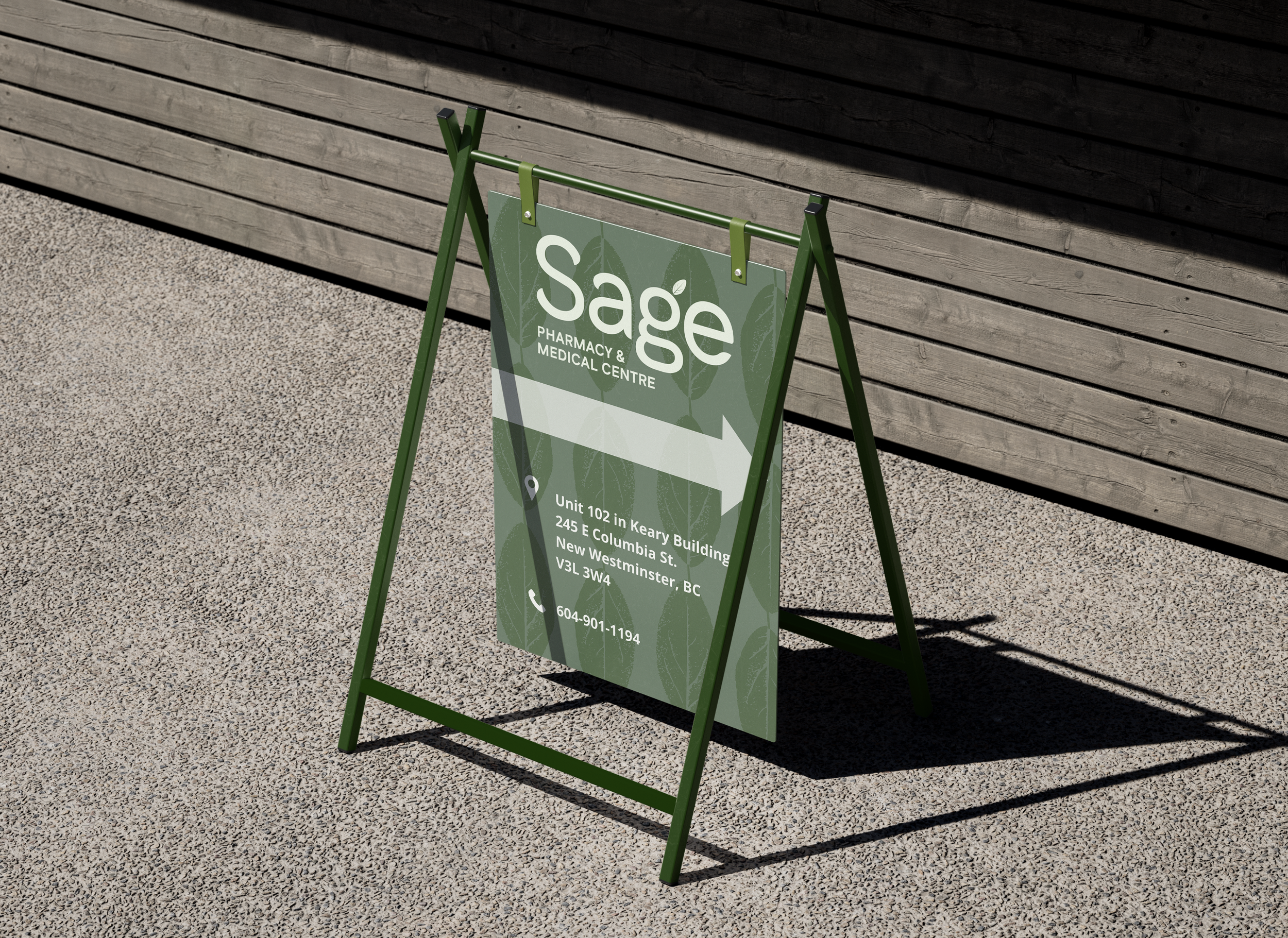 A green A-frame sidewalk sign with a detailed pharmacy and medical centre advertisement, positioned on a textured concrete sidewalk against a wooden wall background, casting shadows.