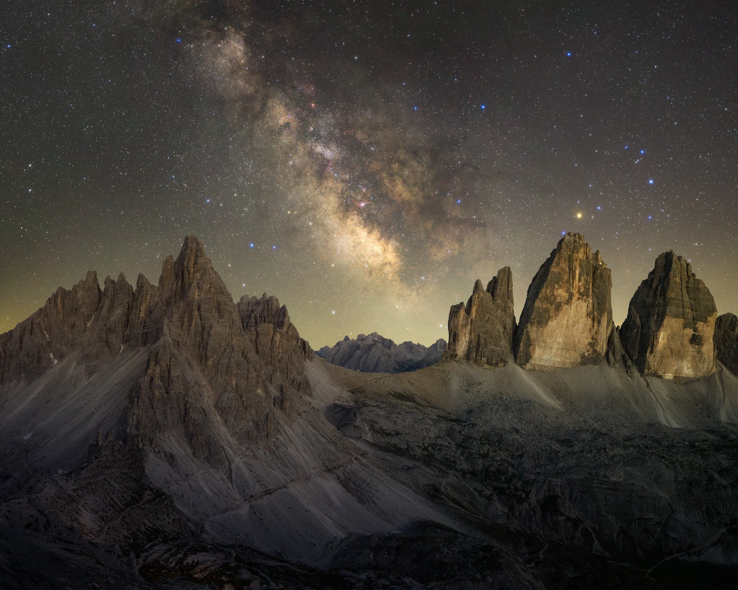 Night sky filled with stars and the Milky Way galaxy above rugged mountain peaks.