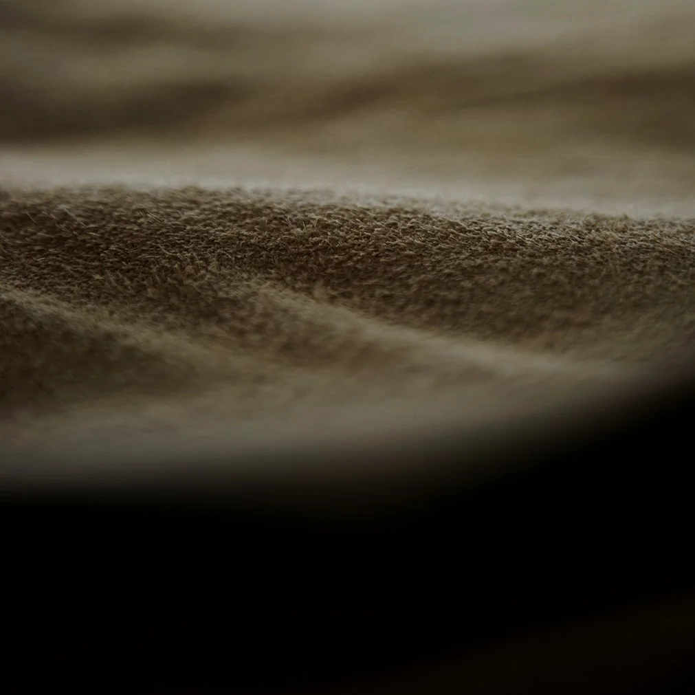 Une surface en tissu ou en velours de couleur marron clair, vue de très près.