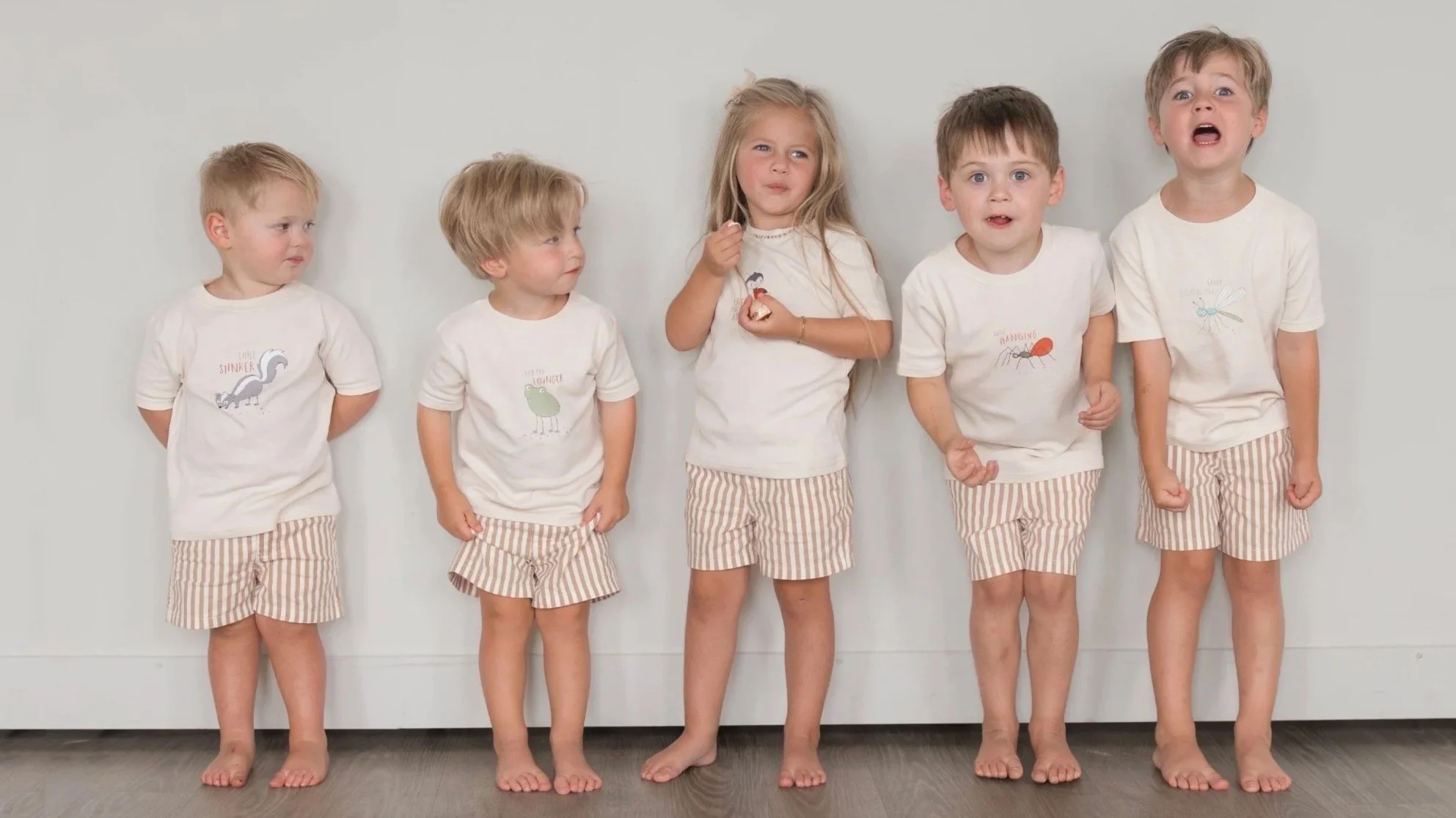 Five children wearing Frank & Ollie illustrated kids clothing, standing together against a simple neutral background.