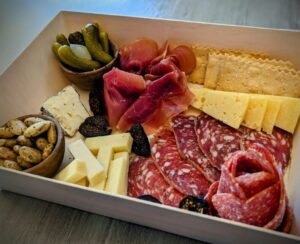 Assorted cheese, cured meats, pickles, and olives in a to go tray from Petaluma Cheese Shop.