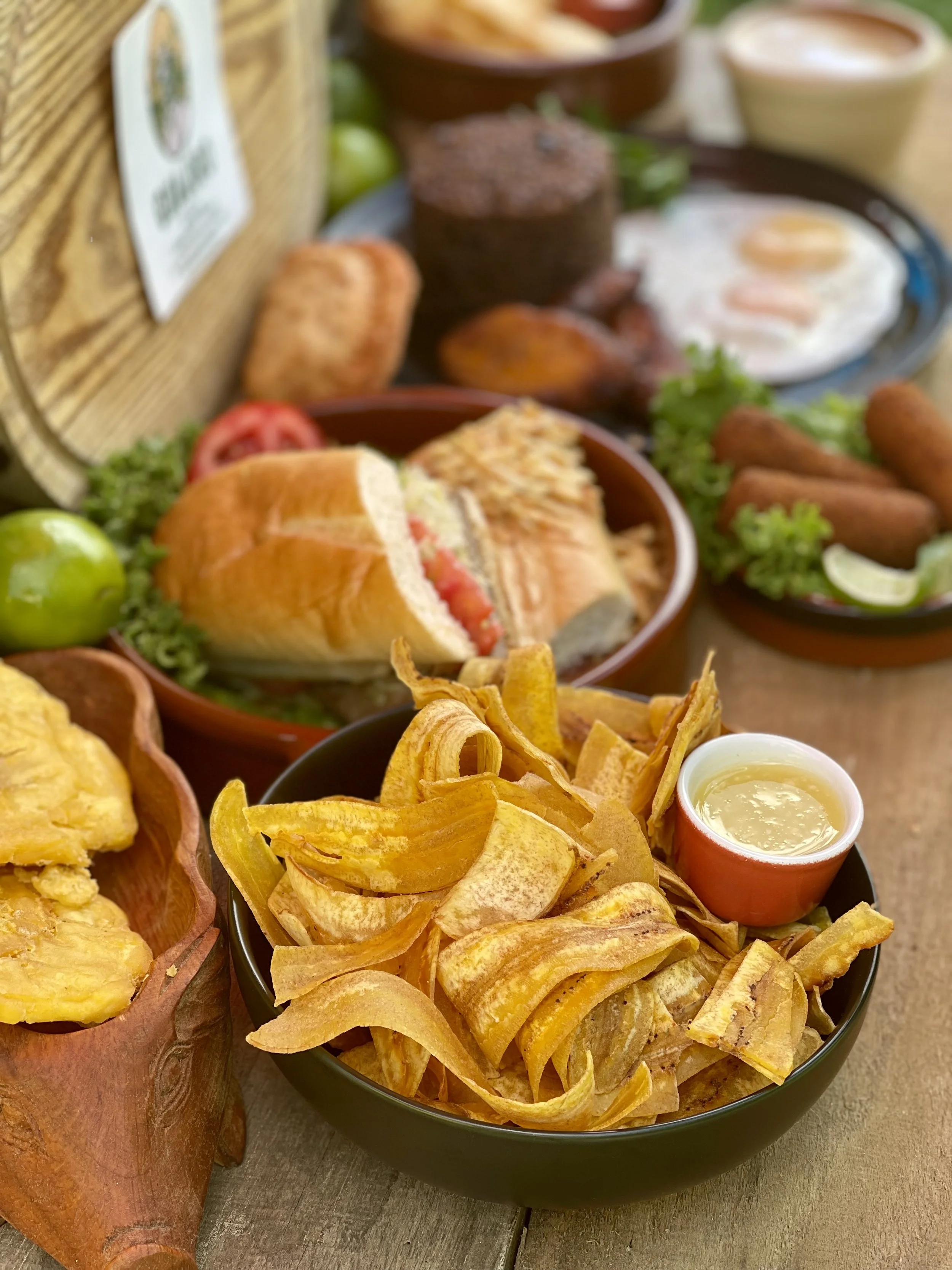 Assorted Cuban dishes including chips and salsa, shrimps, tamale, fried plantains, tostones, and huevos rancheros, with lime and dipping sauces.