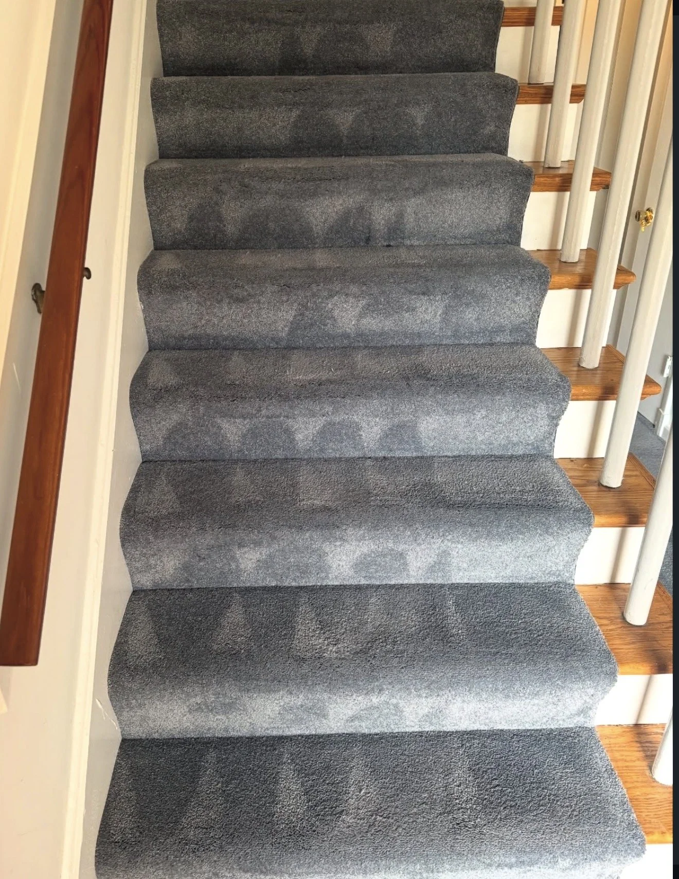 Indoor staircase with gray carpeted steps, white risers, wooden handrail on the left, and wooden treads with white spindles on the right.