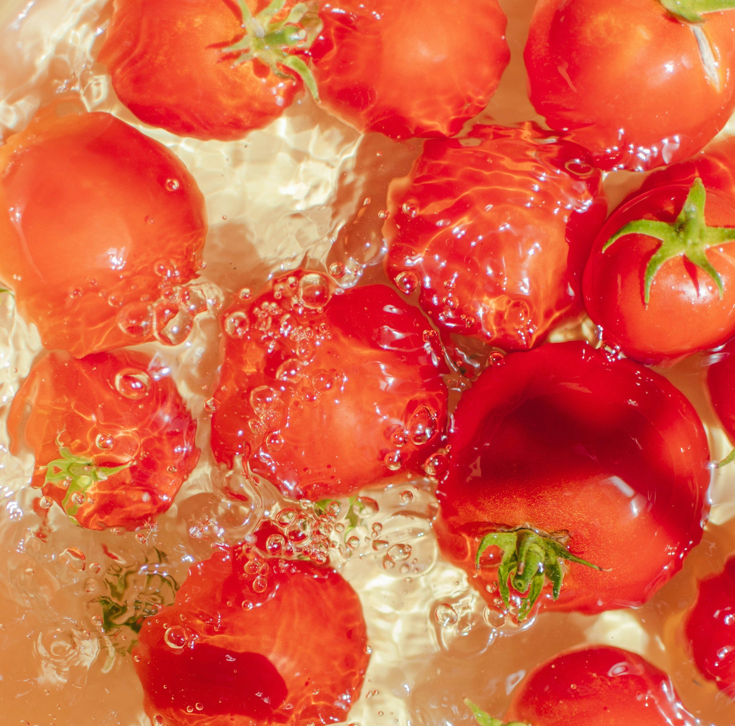 Close-up of ripe red strawberries submerged in water with bubbles.