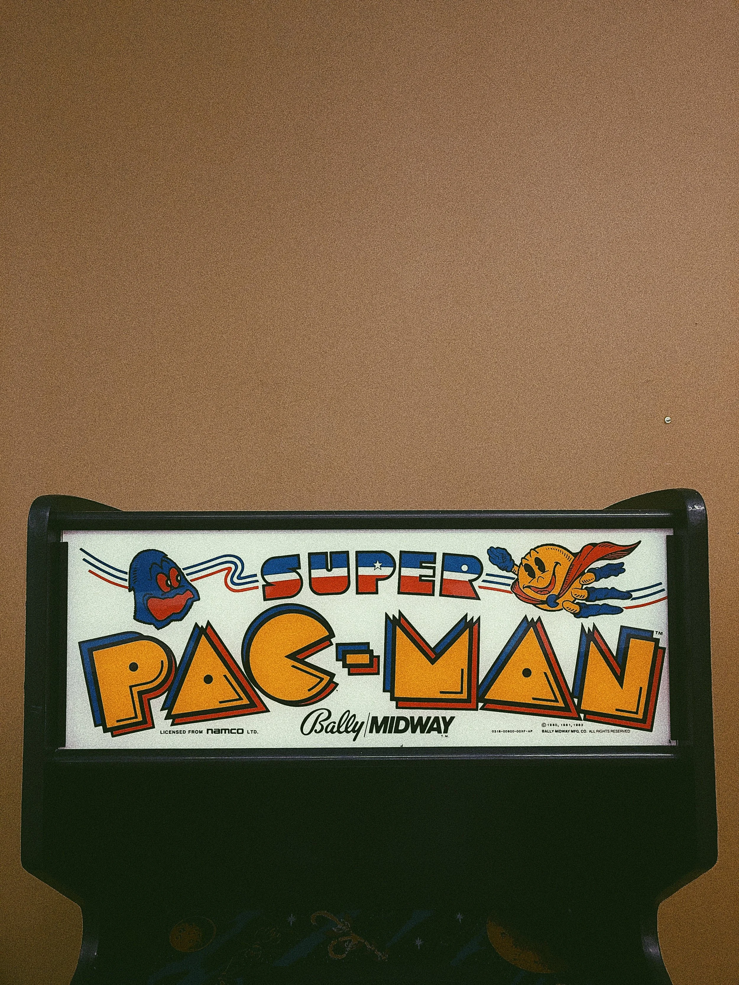 A vintage Pac-Man arcade game marquee featuring Pac-Man and ghosts, with the title in colorful, stylized text, from Bally Midway.