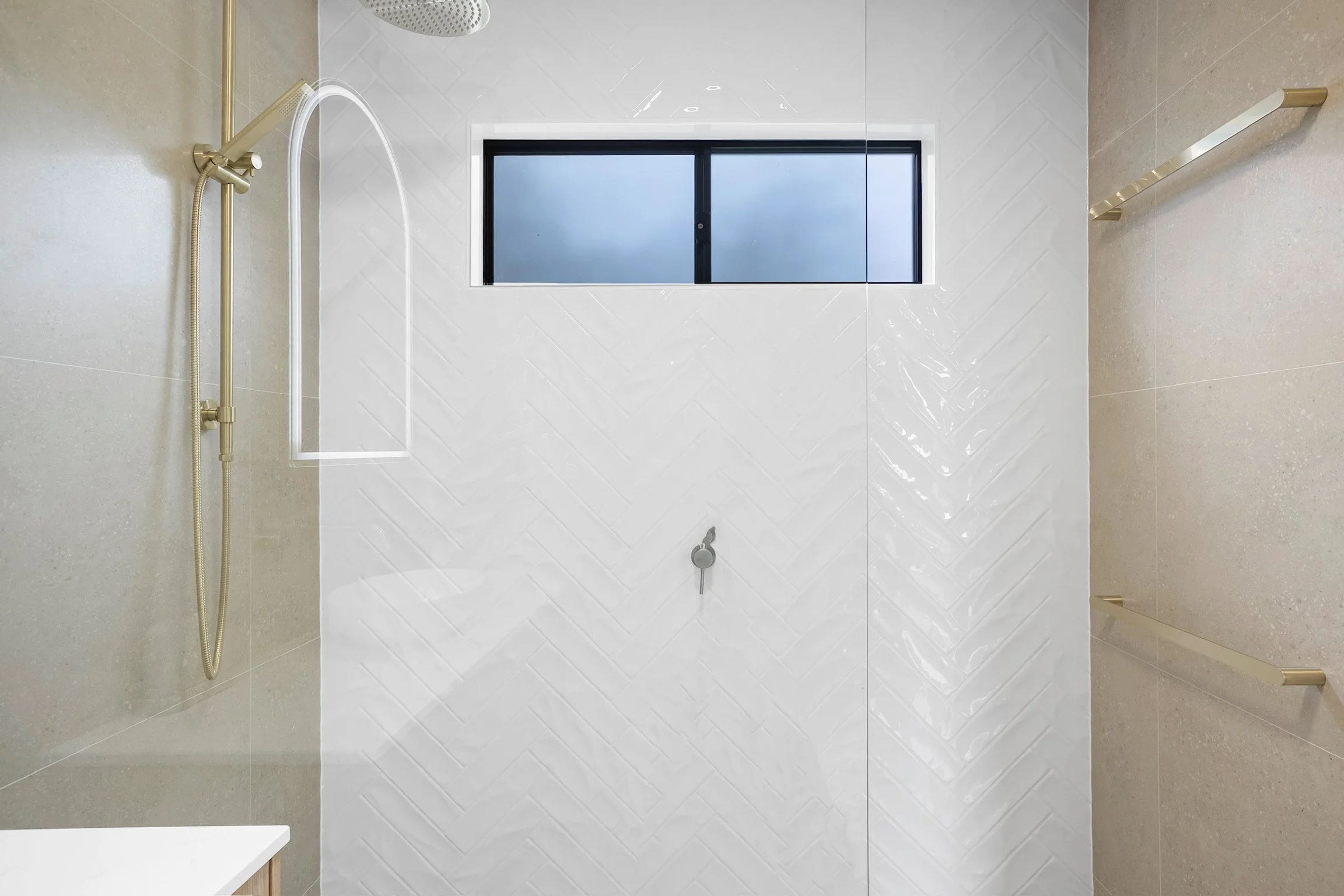 Modern bathroom with a white tiled wall, a frosted window, and a yellowish gold showerhead.