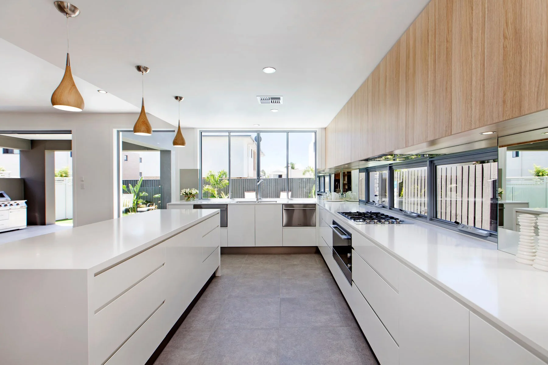 Modern kitchen with white cabinets, large window, wood accents, and pendant lights.