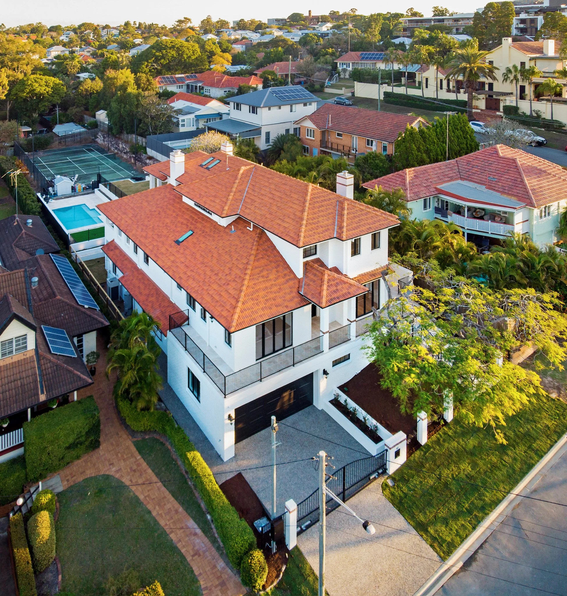 Aerial view of a suburban neighborhood with houses, greenery, and solar panels on rooftops.