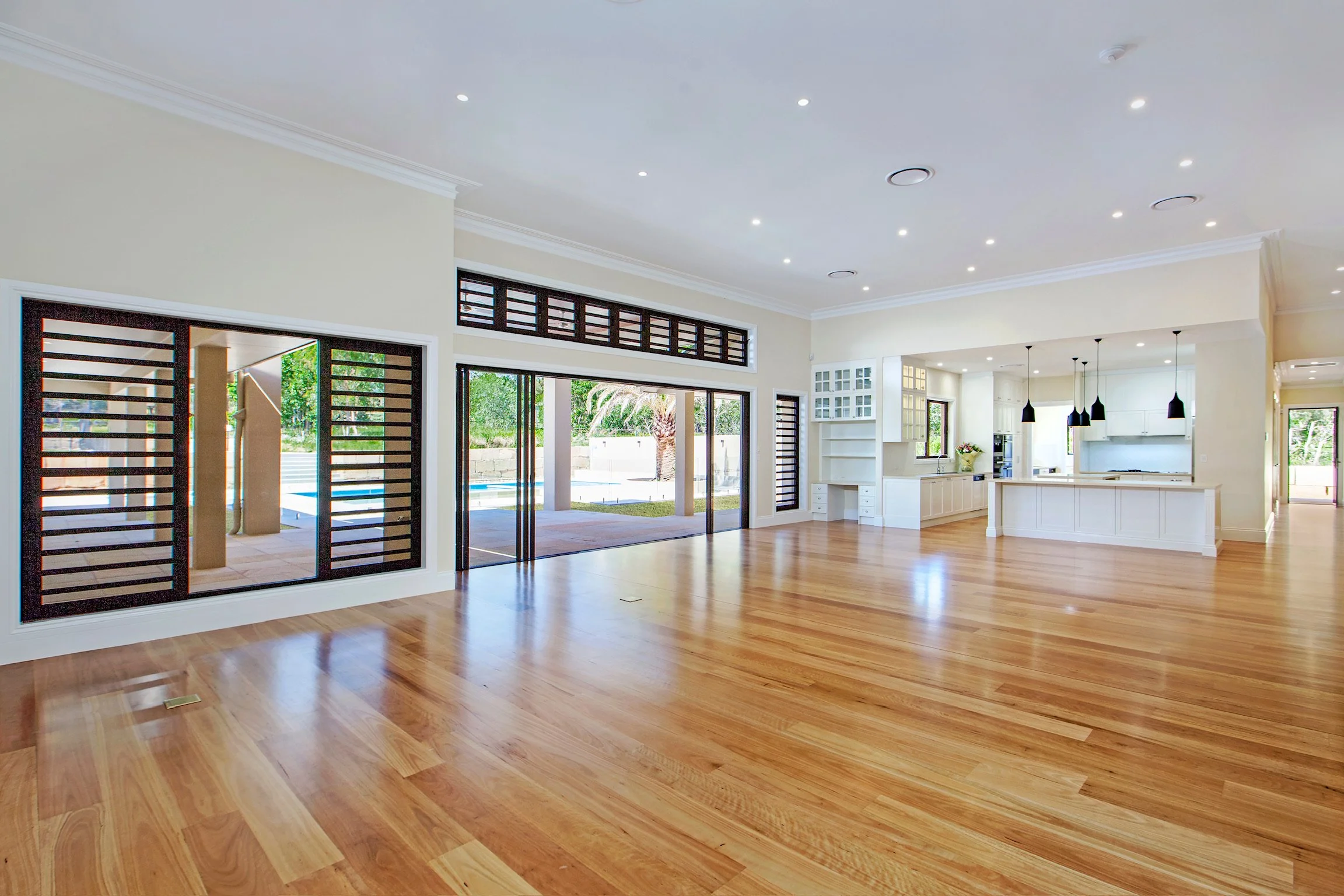 Spacious living room with hardwood floors, large windows, and an open kitchen with white cabinets and a central island.