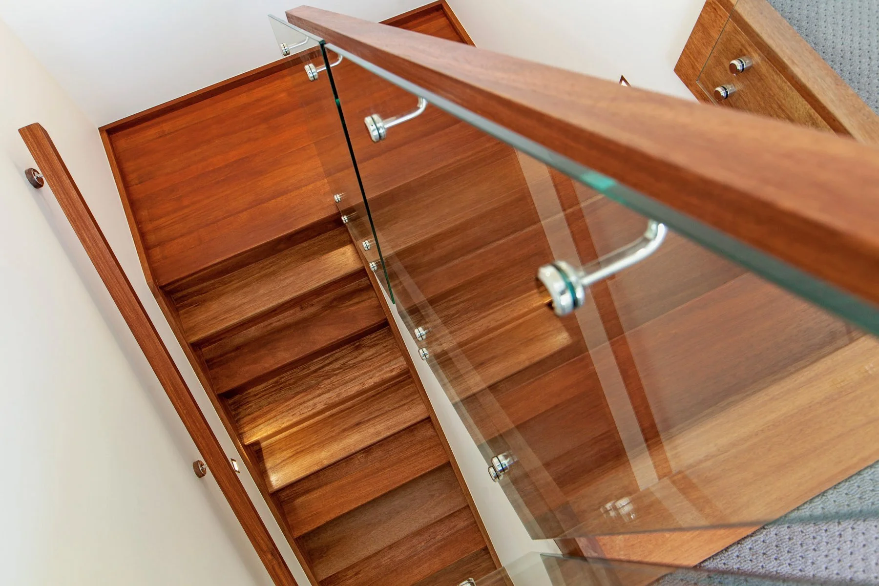 Wooden display cabinet with glass doors and shelves in a room with beige walls and brown carpet.