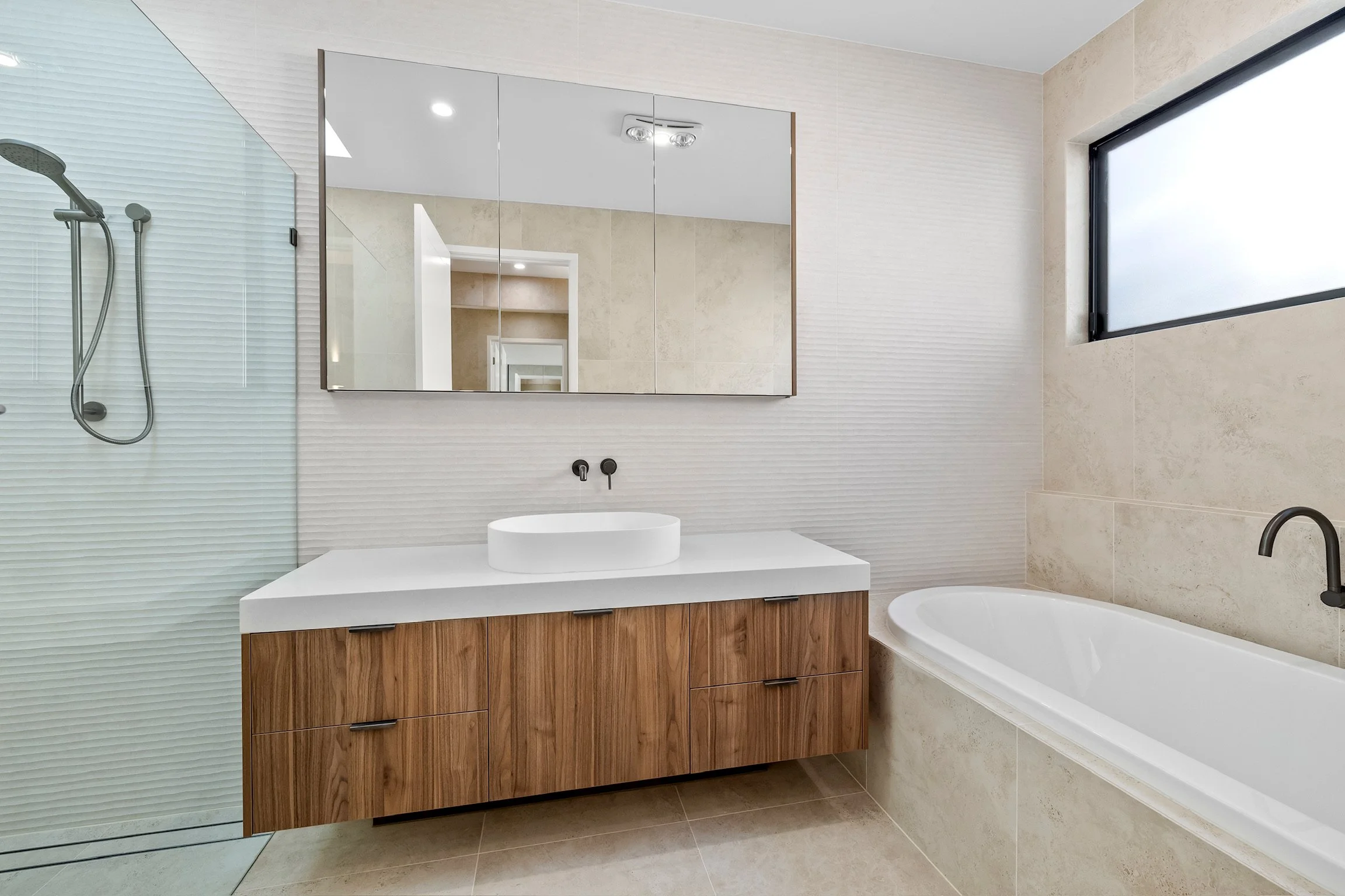 Modern bathroom with a walk-in shower, a wooden vanity with a vessel sink, a bathtub, and a large frosted window.