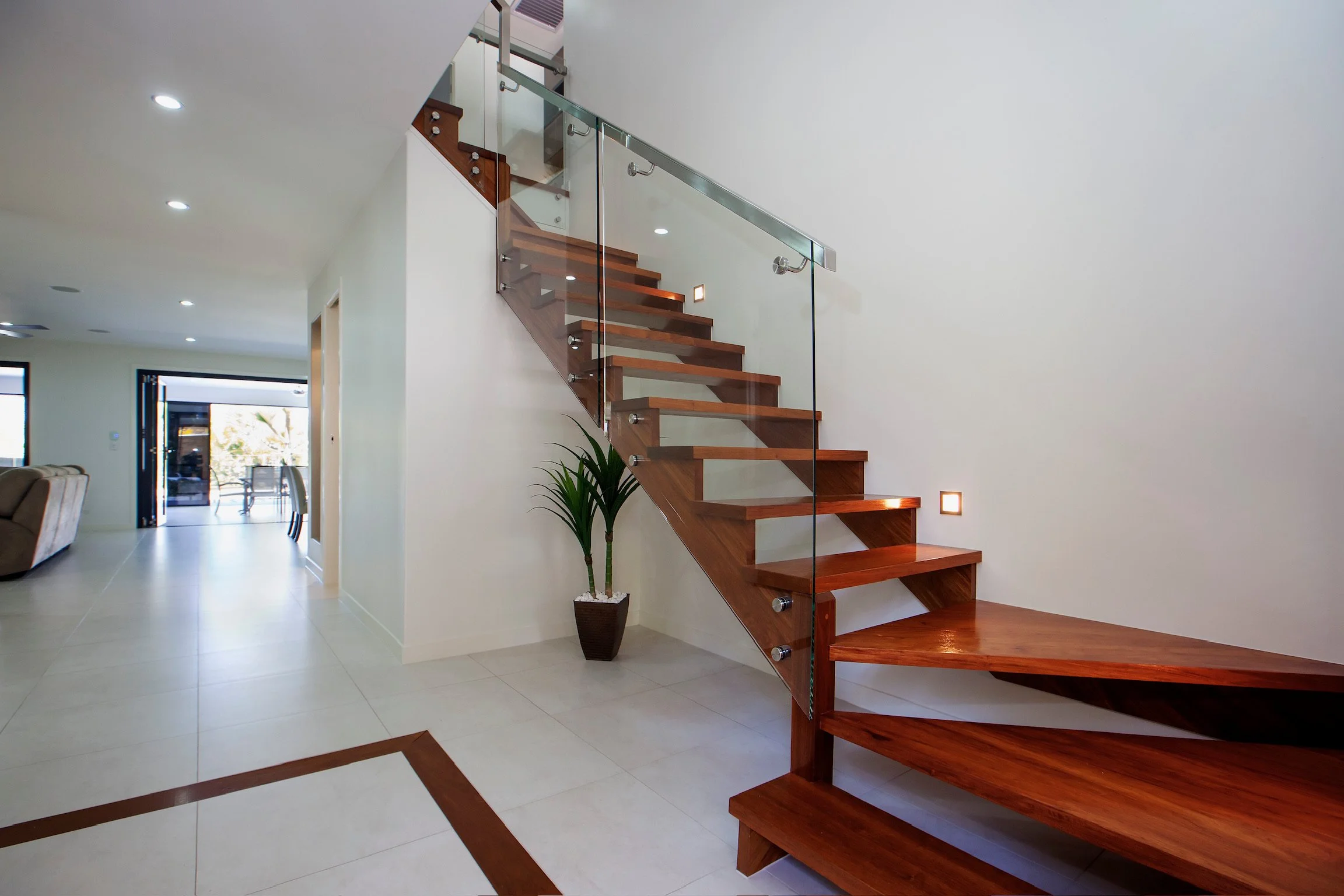 Wood staircase with glass railing in a modern home interior.