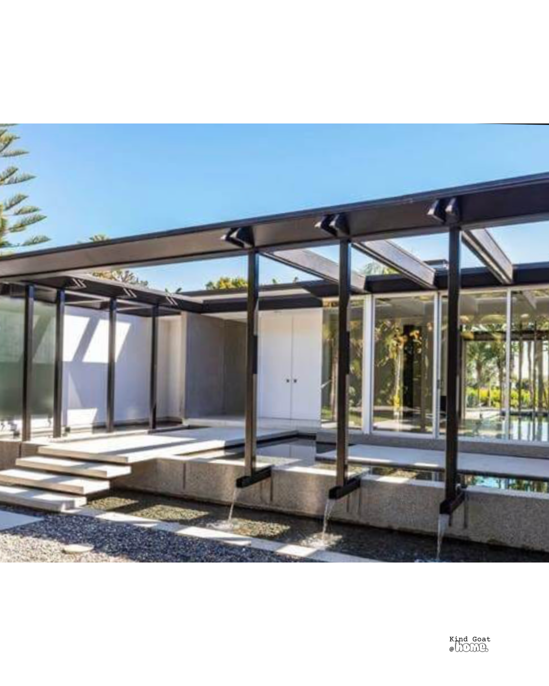 Modern house with large glass windows, black metal framework, outdoor steps, and a water feature underneath.