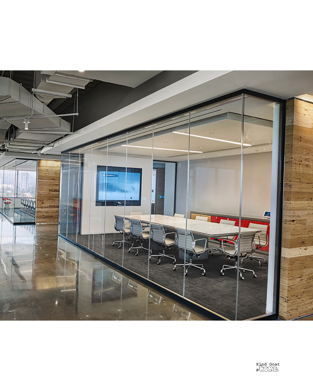 Modern conference room with glass walls, a large table, and chairs, located in an office building with city views.
