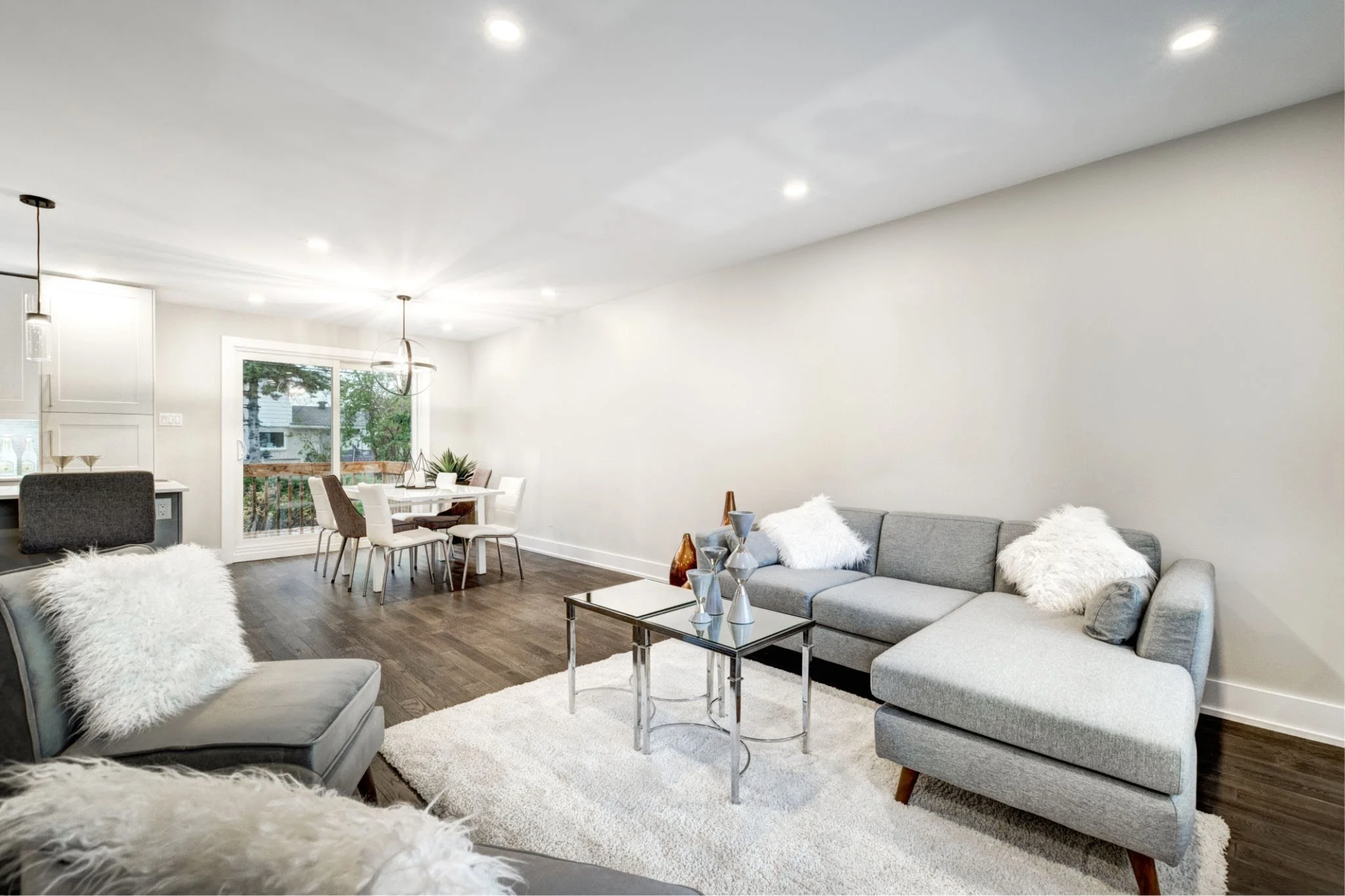 rofessionally staged open-concept living and dining room in a Halifax home featuring a grey sectional, plush white rug, glass nesting coffee tables, and natural lighting.