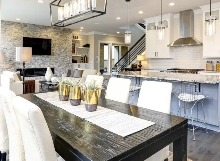 Staged modern open-concept home in Halifax, Nova Scotia, featuring a stone fireplace and granite kitchen island, with text overlay detailing a +12% average sale price increase for staged listings in the $400k-$600k range.