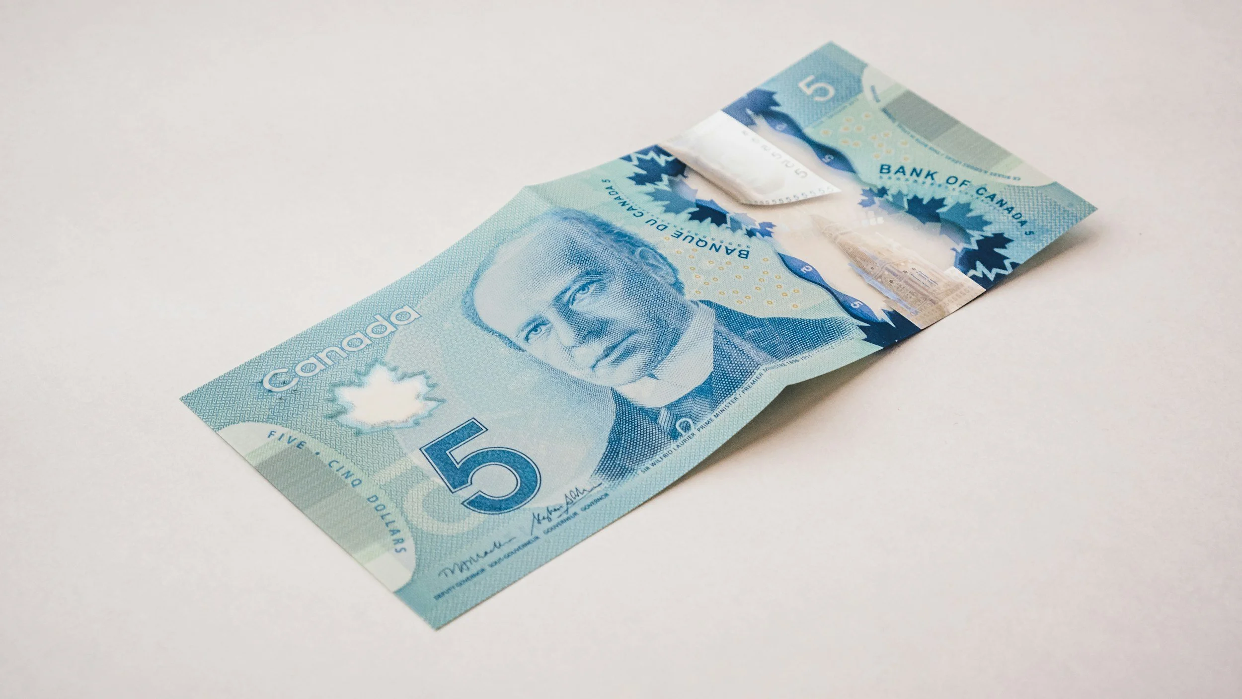 Front of a blue polymer Canadian five-dollar bill featuring Sir Wilfrid Laurier and a transparent security window.