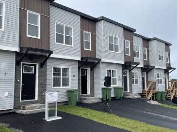 Newly built two-story grey vinyl and brown panel townhouses at YWCA Mount Hope Village in Dartmouth, Nova Scotia.