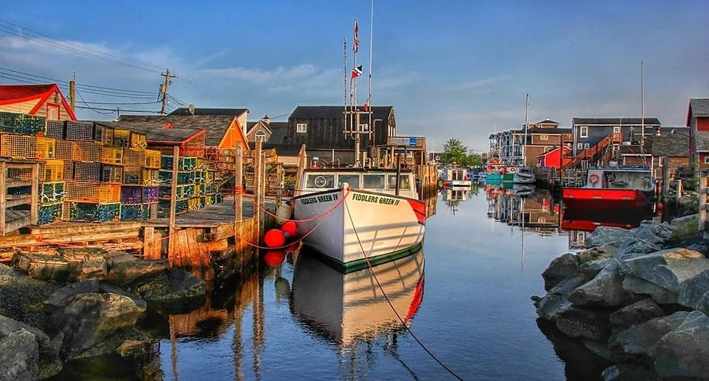 Fishing boat docked along colorful boardwalk shops and lobster traps at Fisherman's Cove in Eastern Passage.