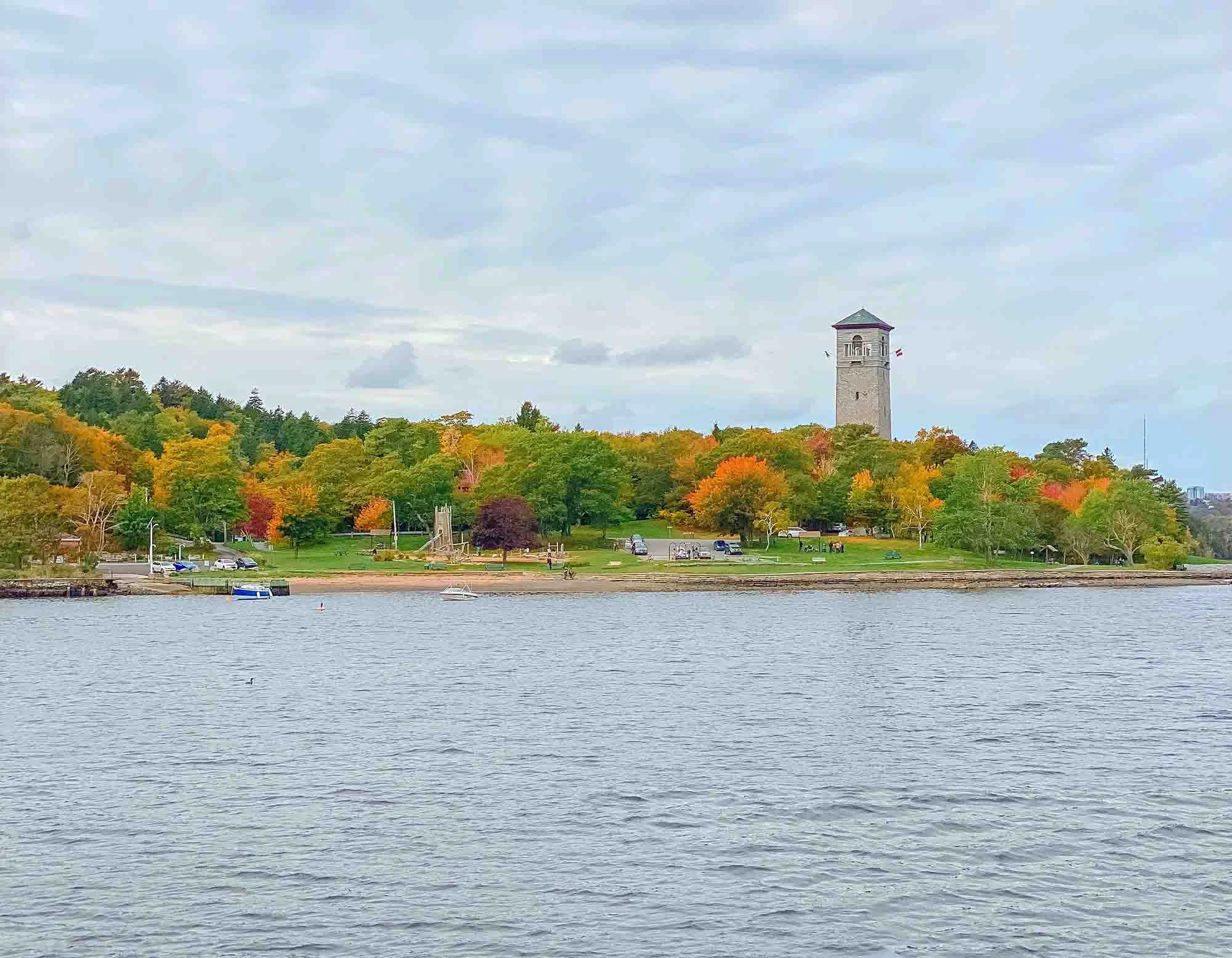 View from the water of the Memorial Tower at Sir Sandford Fleming Park surrounded by vibrant fall trees along the Northwest Arm shoreline in Halifax.