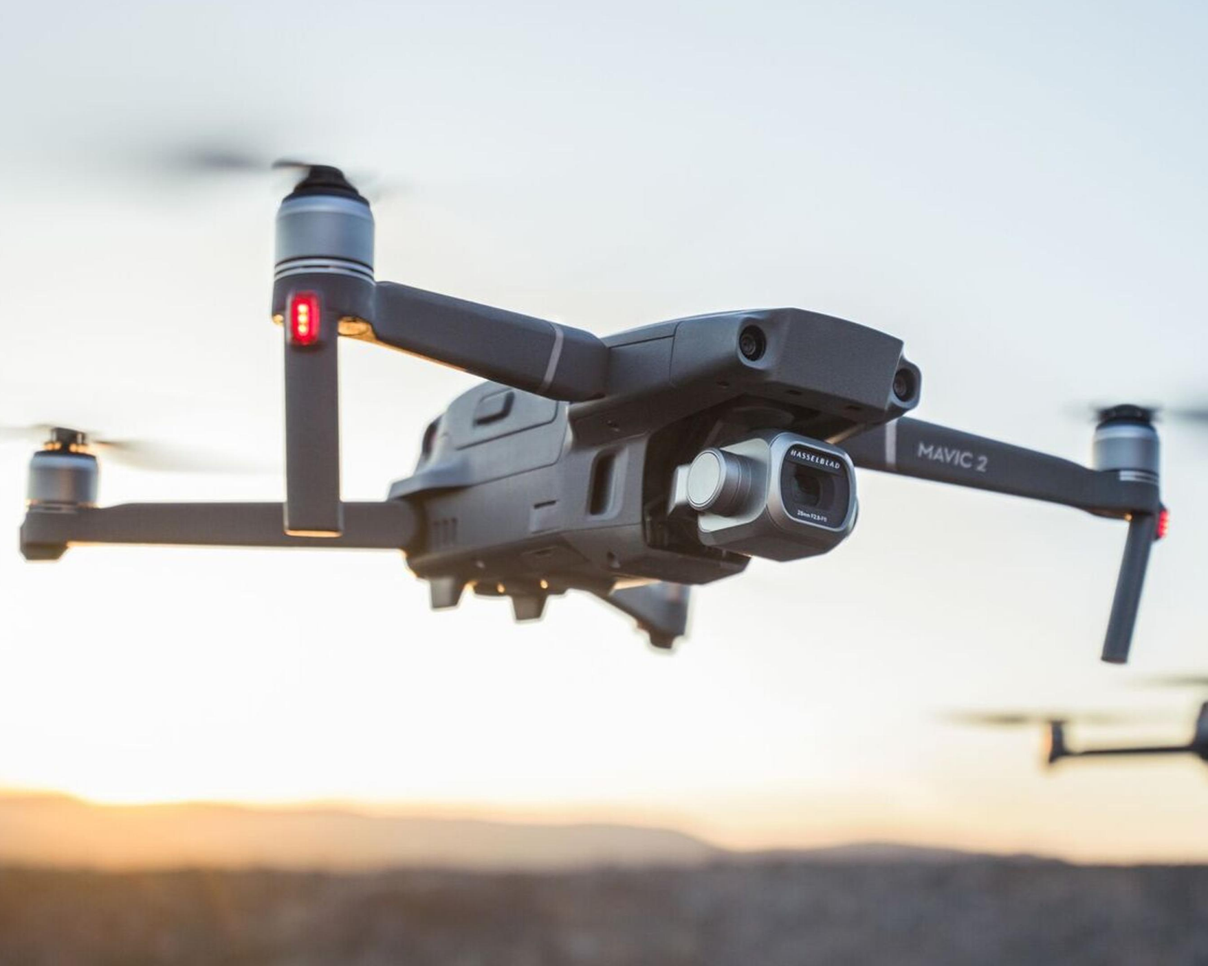 A drone flying outdoors during sunset with a clear sky.