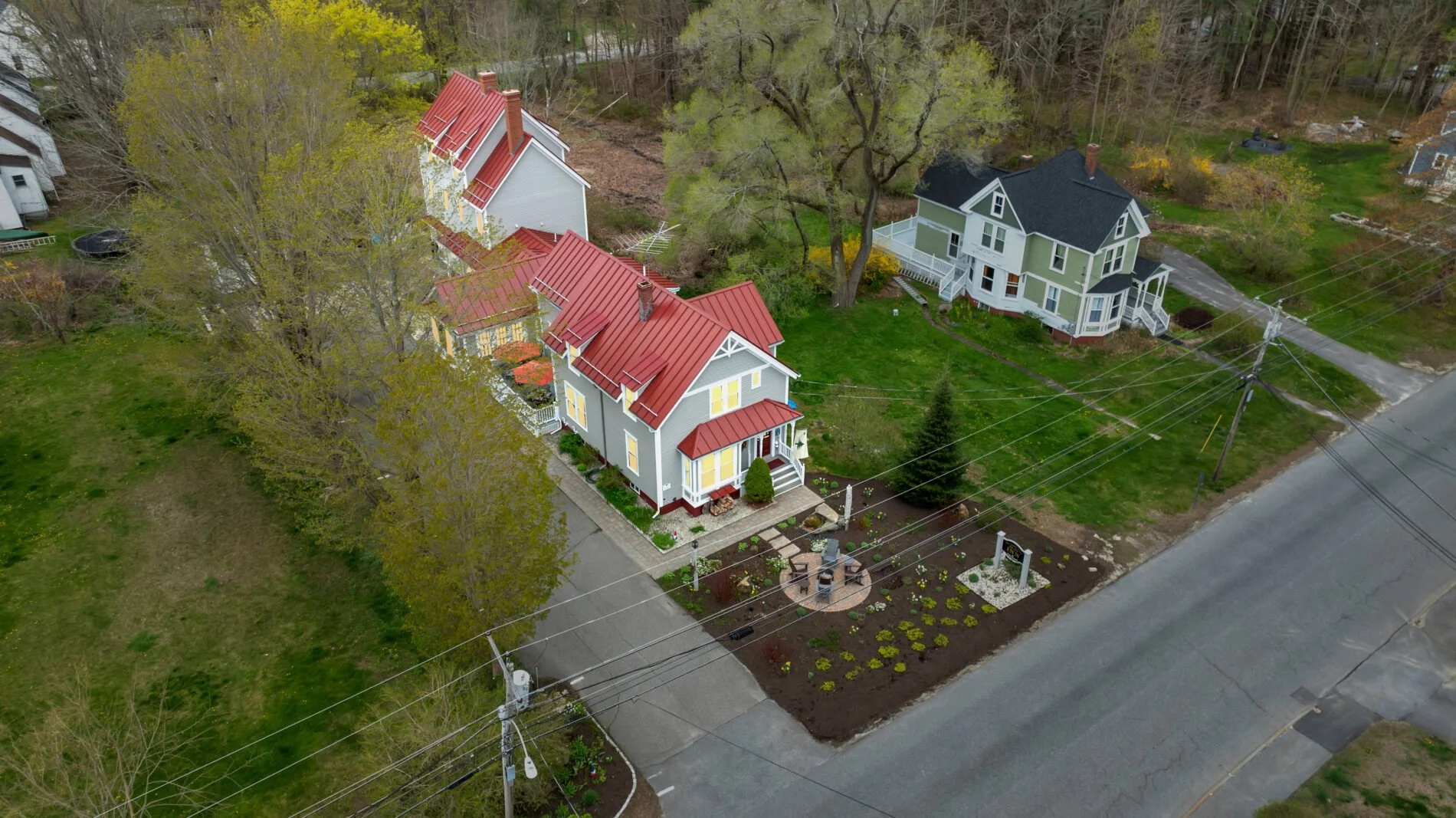 Aerial view of the James Place Inn in Freeport, Maine. The inn is a Victorian style home, painted grey, and a red metal roof.