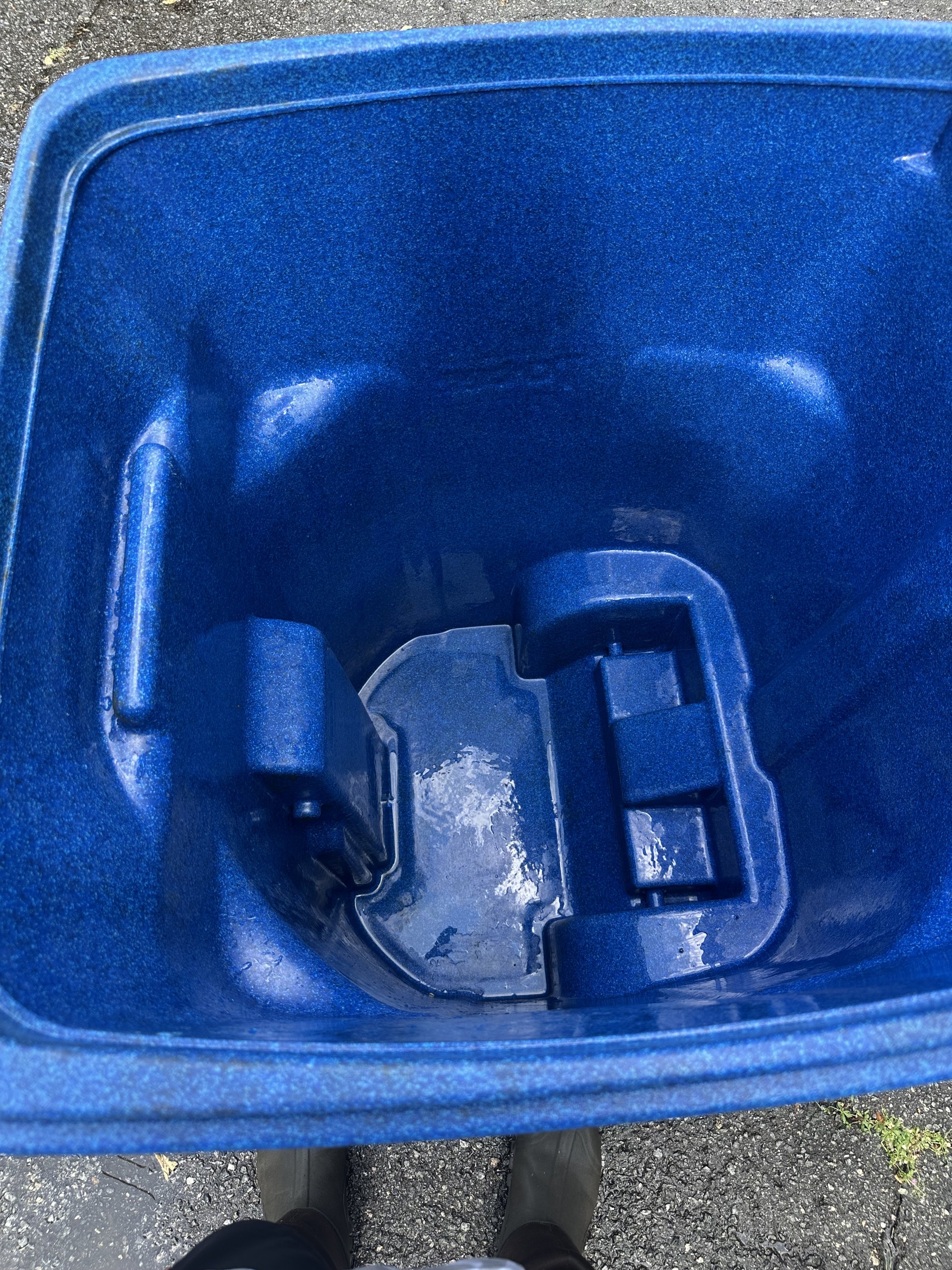 Looking down into an empty blue plastic trash can that has been pressure washed.