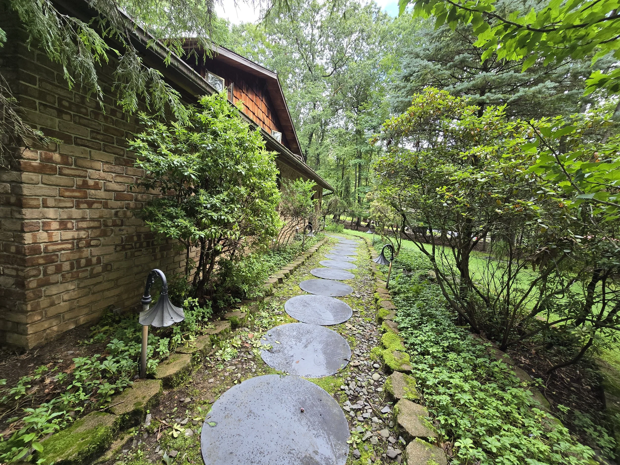 Stone stepping stone pathway alongside the warm brick exterior of New Soil Sober Living men's residence in Northeast Pennsylvania