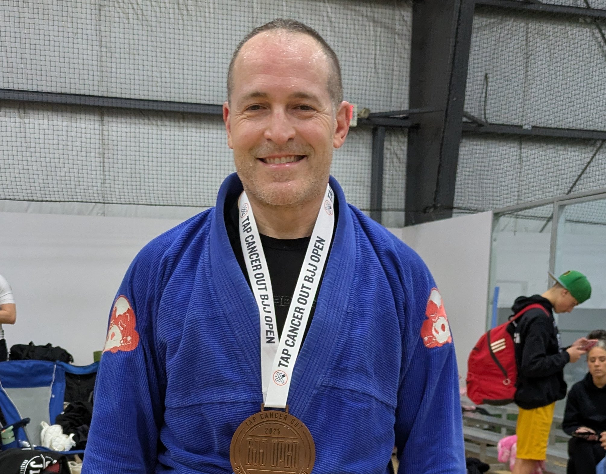 Bert, US Marine Corps veteran and founder of New Soil Sober Living, wearing a blue Brazilian Jiu-Jitsu gi and tournament medal, celebrating continuous sobriety since 2009.