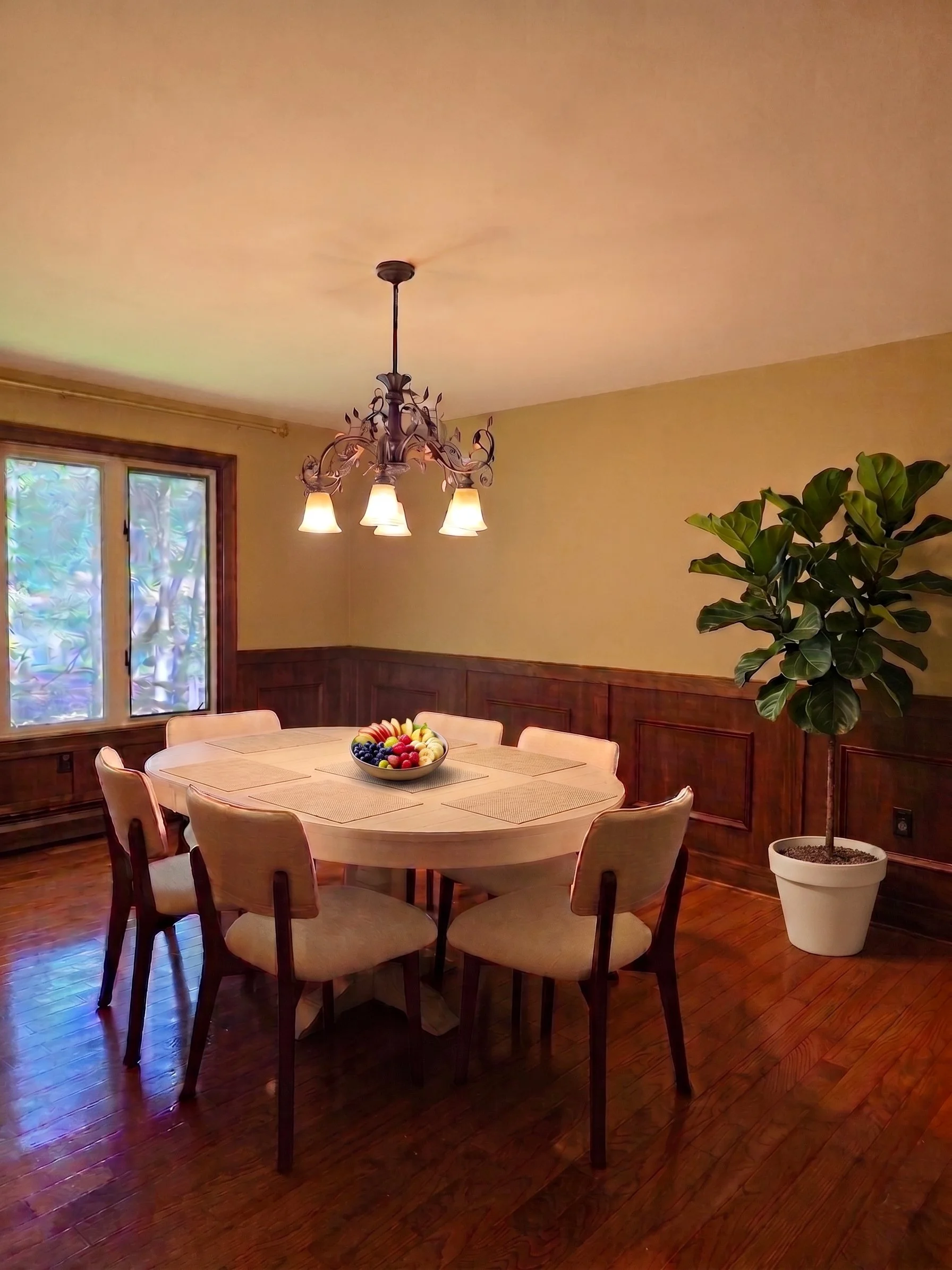 Warm communal dining room with a large oval table, hardwood floors, and fresh fruit bowl at New Soil Sober Living for men in Northeast Pennsylvania