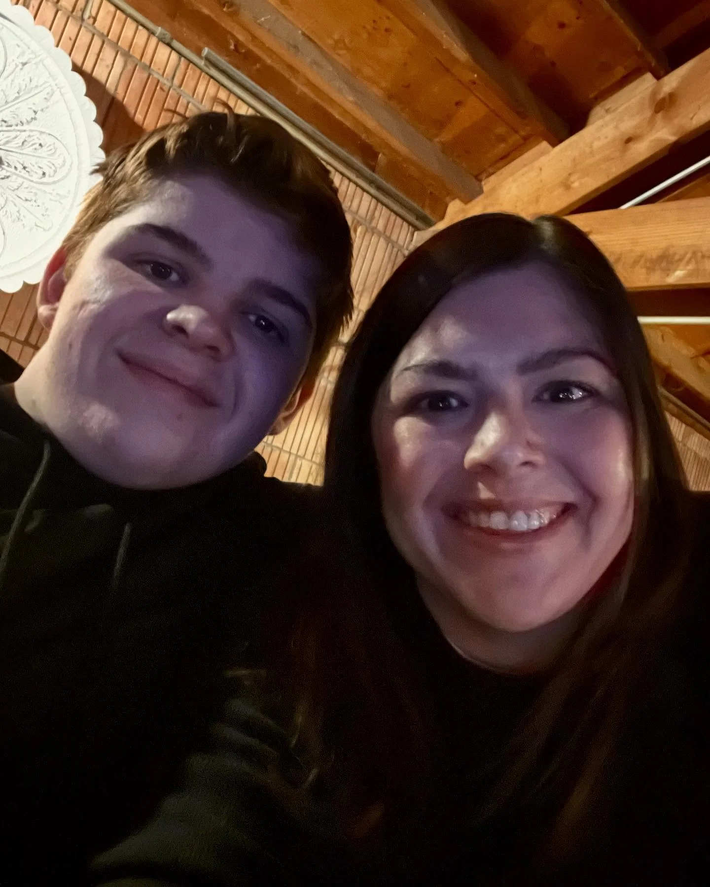 A smiling young man and woman taking a selfie in a wooden interior setting.