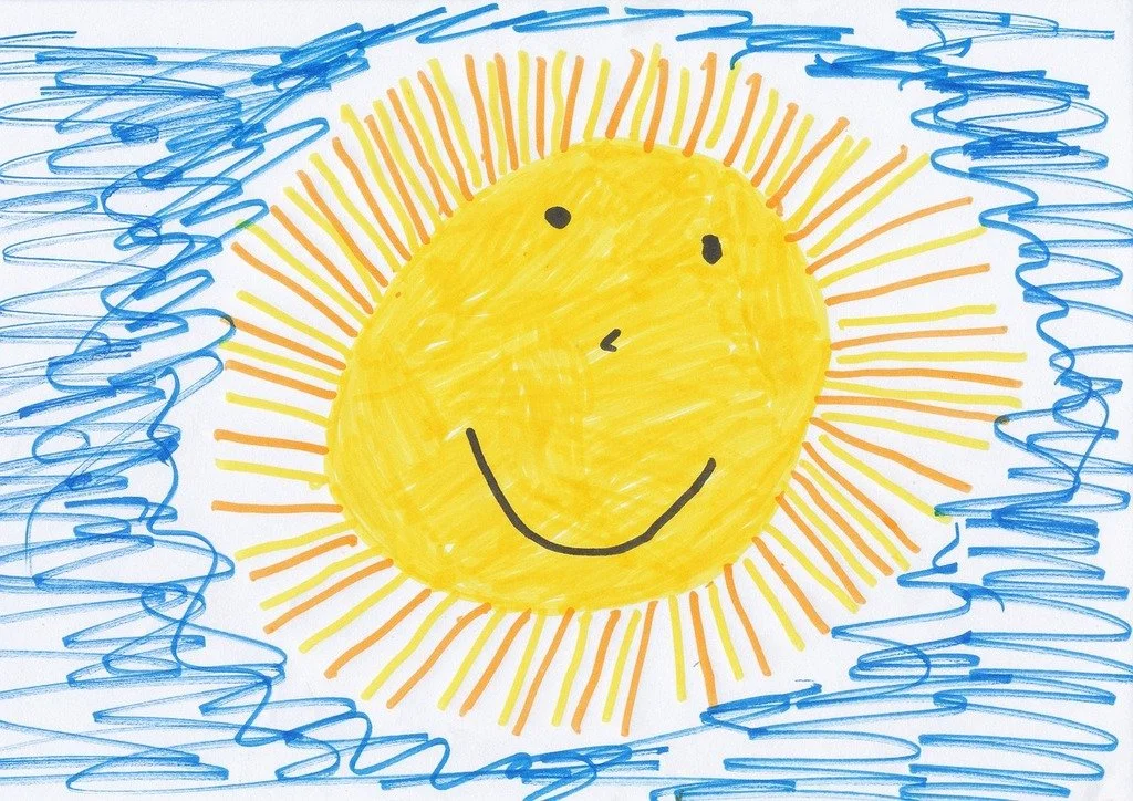 Child's drawing of a smiling sun with a yellow face and orange rays, surrounded by blue scribbles representing the sky.