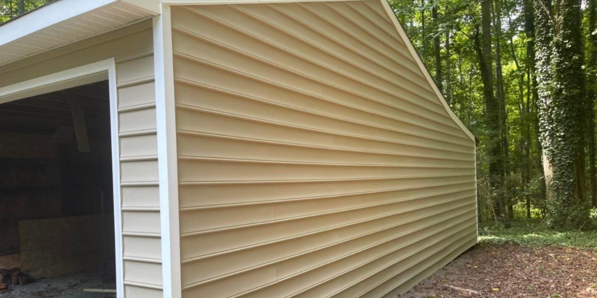 Side view of a beige metal storage building with a partially open door, surrounded by trees and woodland.